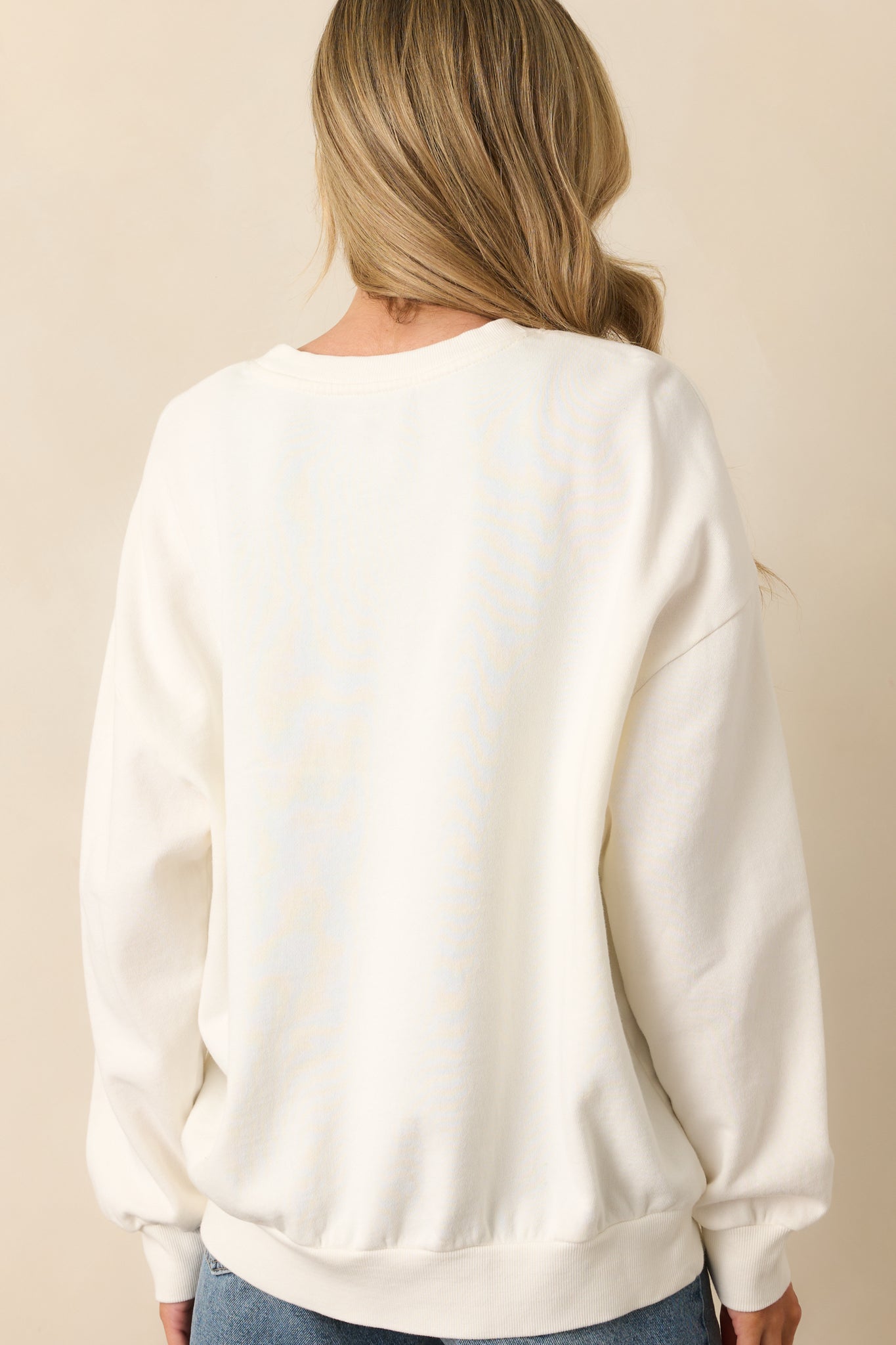 A view from behind displaying the plain ivory back and relaxed fit of the oversized sweatshirt.