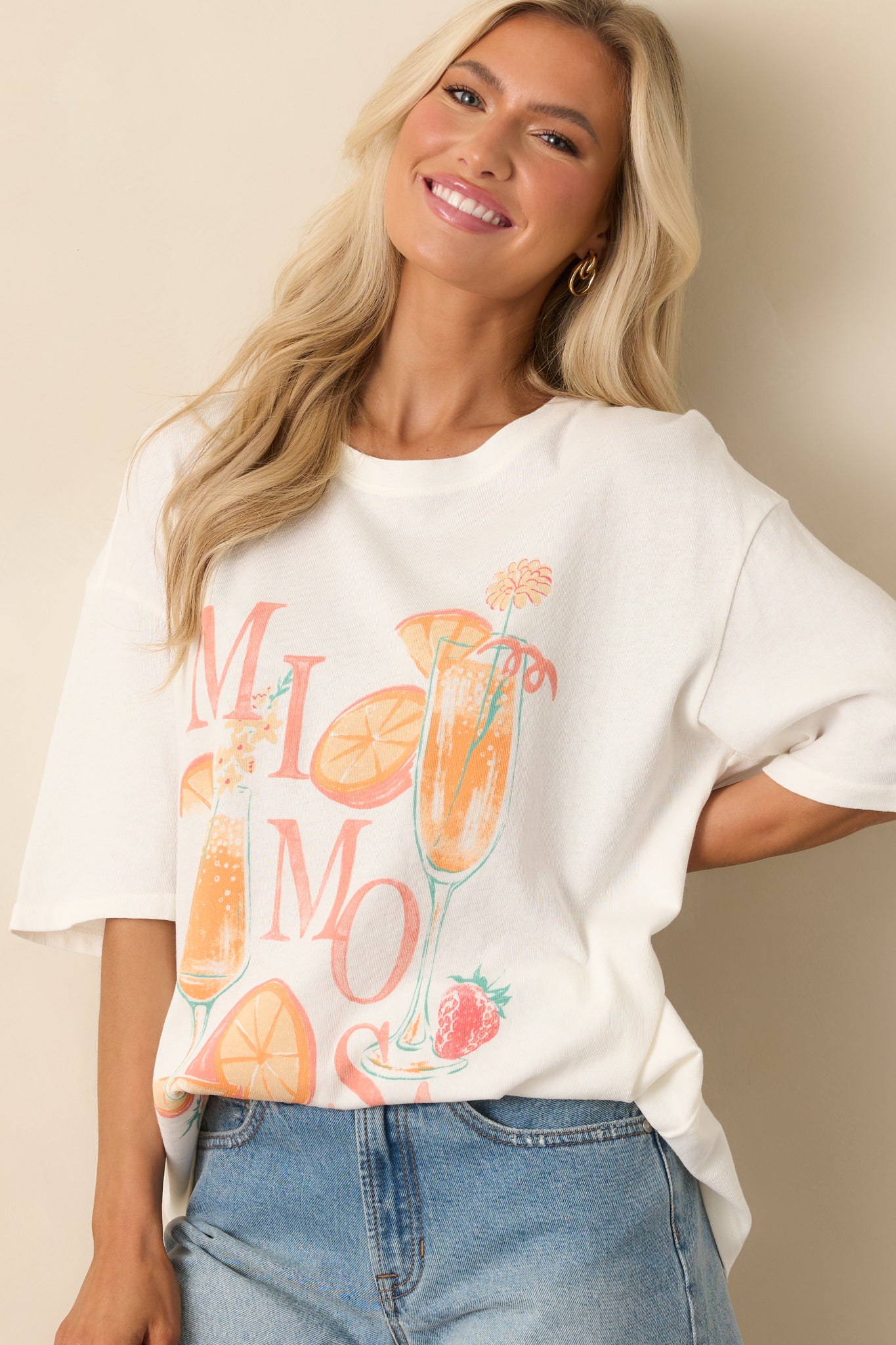 Partial view of the ivory crew neck tee, showing short sleeve construction and a portion of the front design.