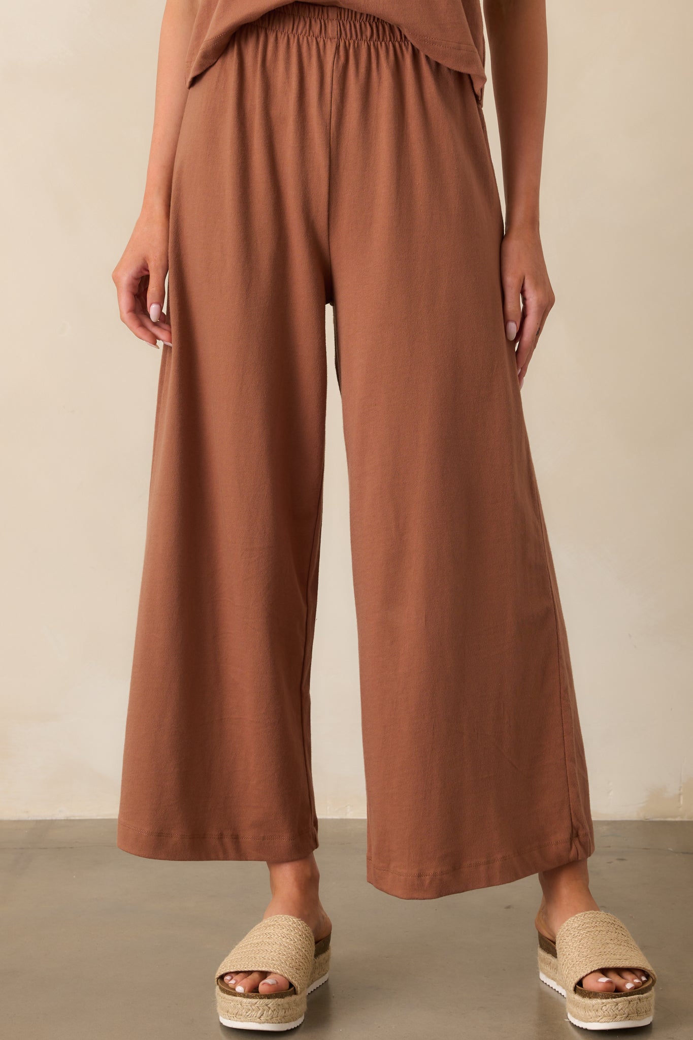 Close-up of the elastic waistband and smooth fabric texture of the brown jersey pants.