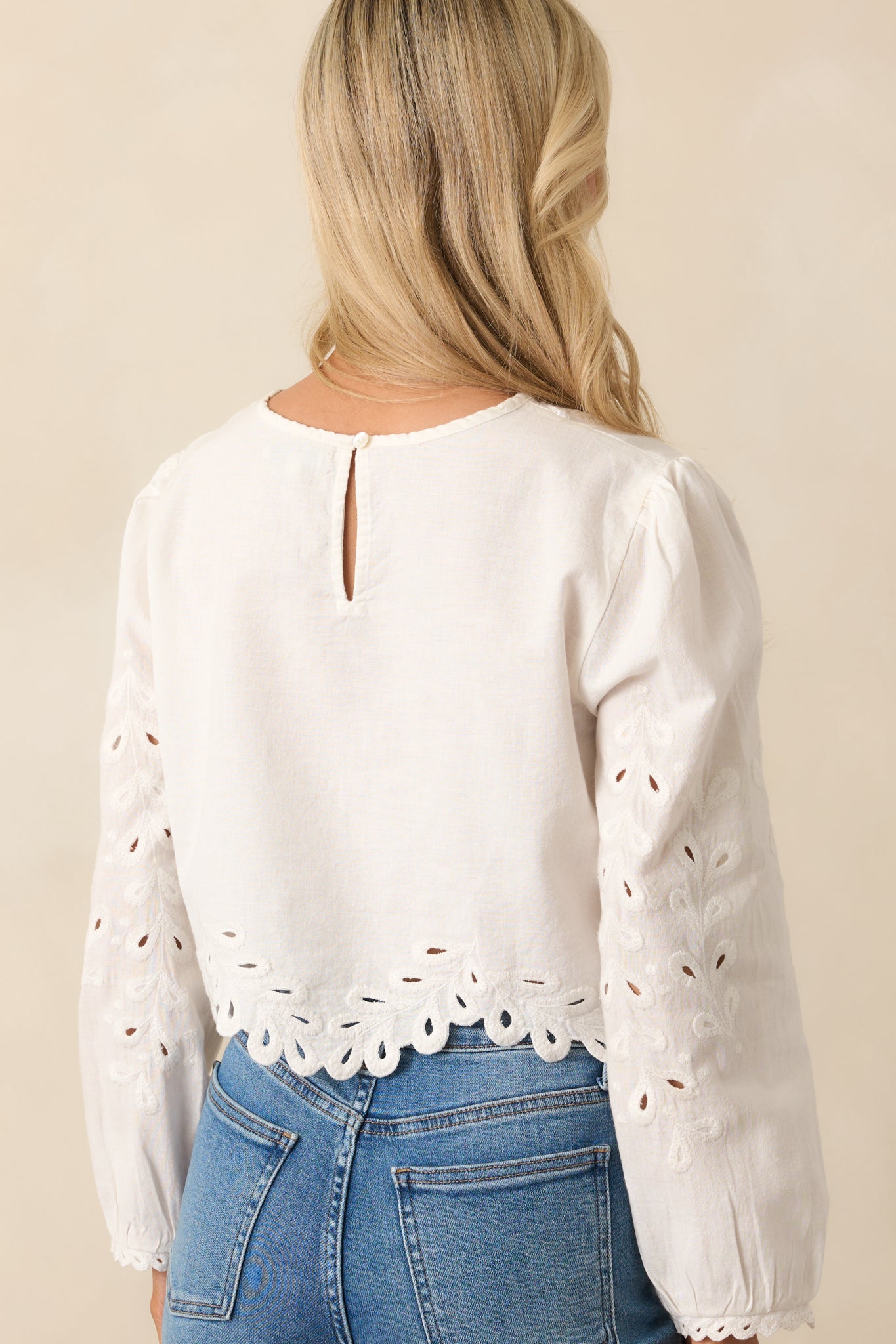 A view from behind of the white top, featuring the back keyhole button closure and embroidered detail throughout.