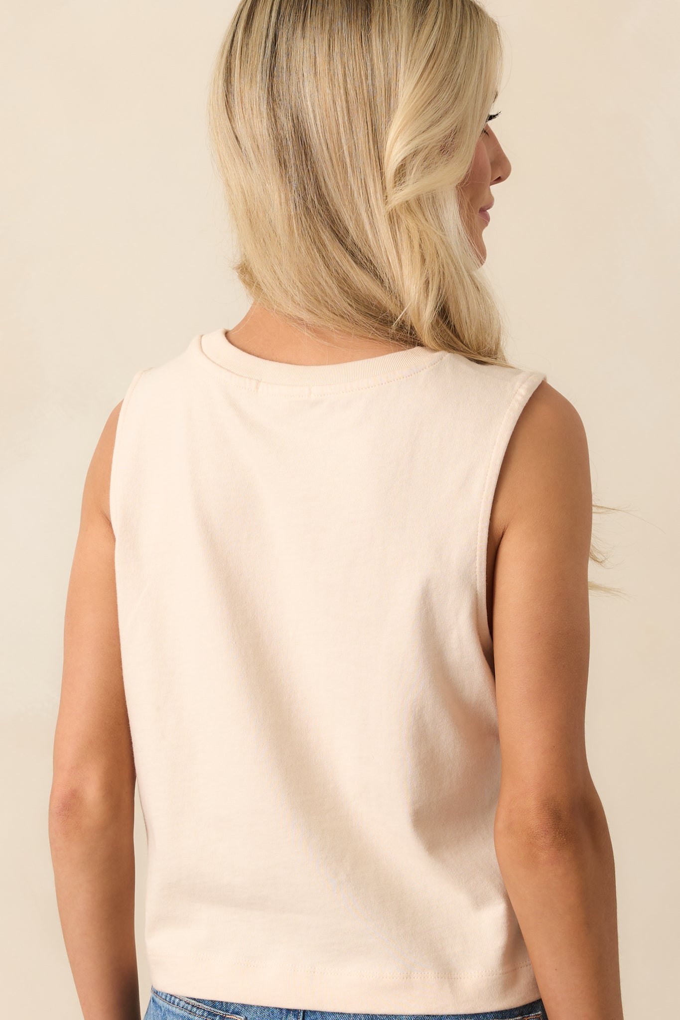 Rear view showing the high back cut and ribbed fabric of the beige cropped tank top.