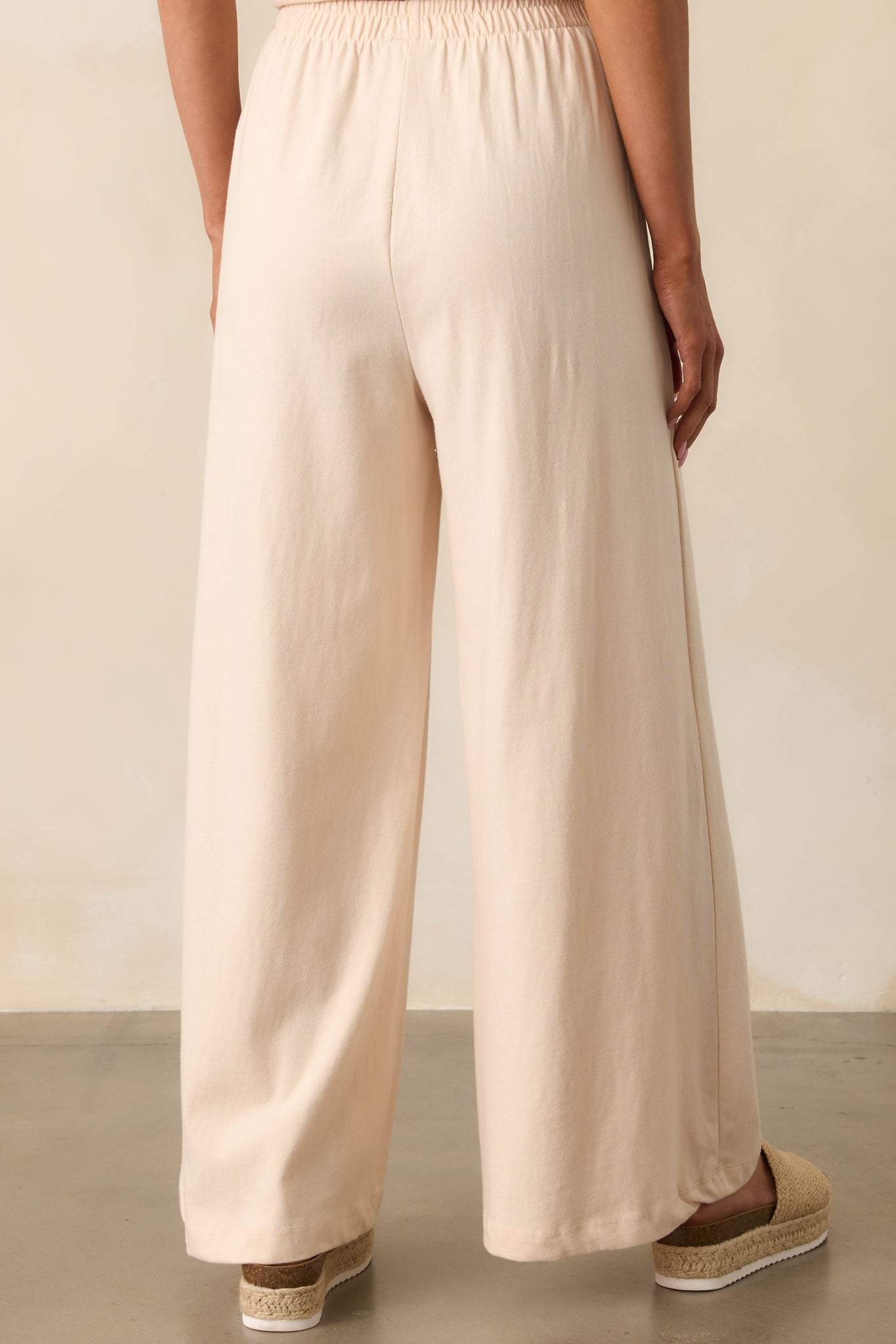 A view from behind of the beige wide-leg pants, focusing on the relaxed fit and high-rise elastic waistband.