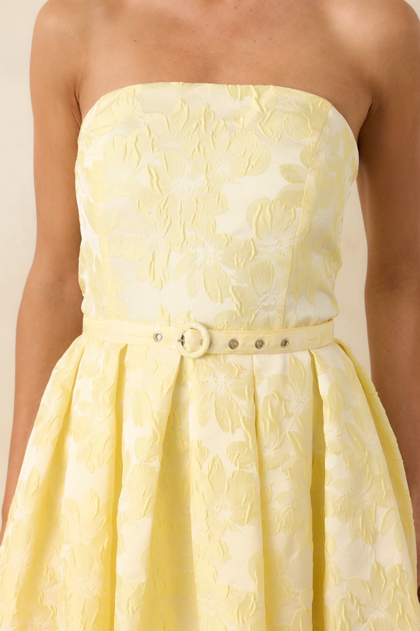 Close view of matching belt with delicate buckle and pleated fabric detail.