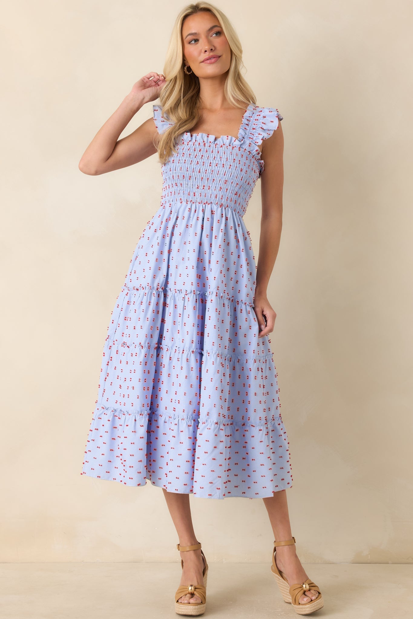 Blue gingham dress featuring ruffled straps, a smocked bodice, and a softly draped midi-length silhouette.