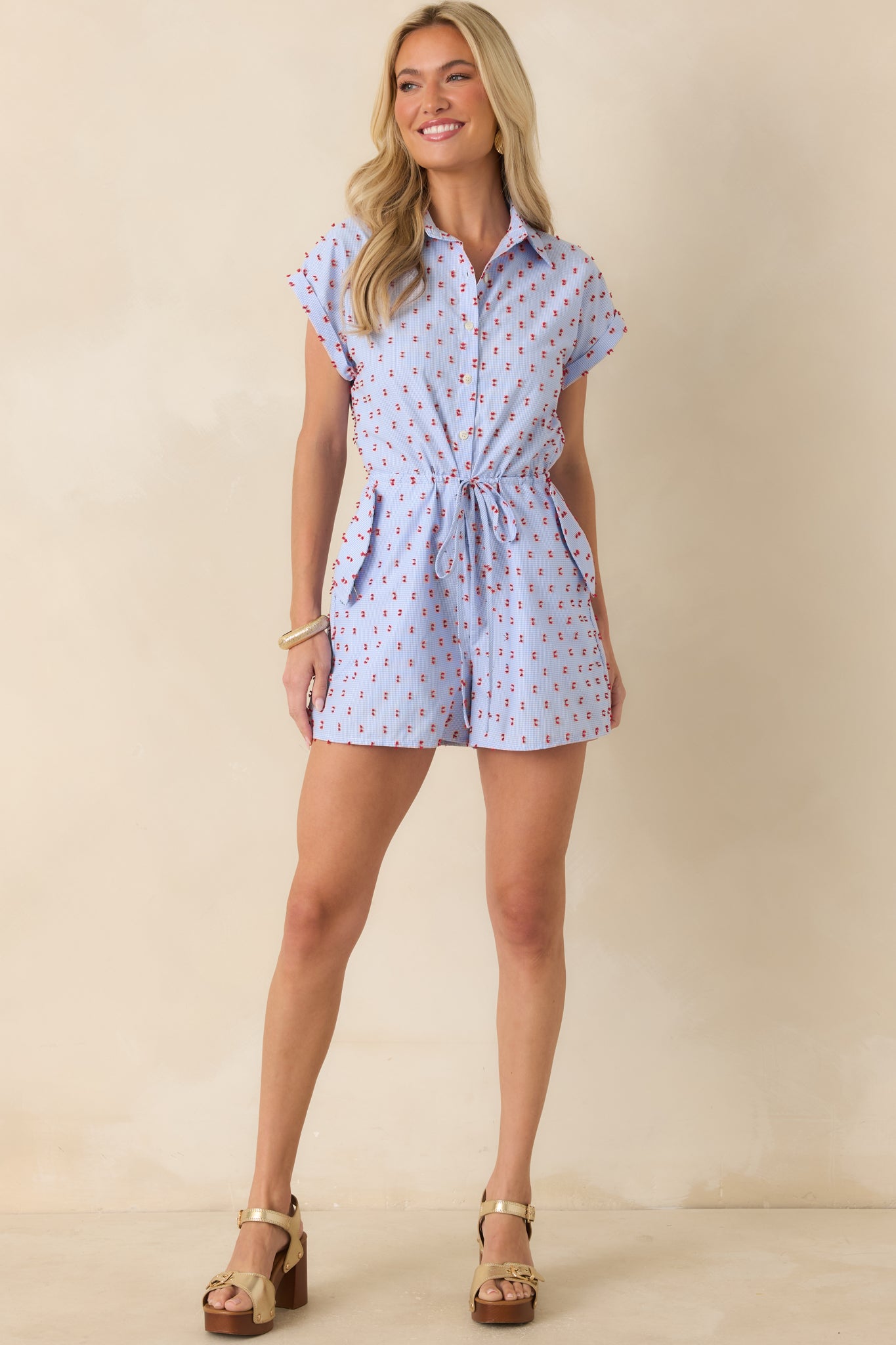 Blue checkered romper showcasing patch pockets with button accents, embroidered details, and an easy relaxed fit.