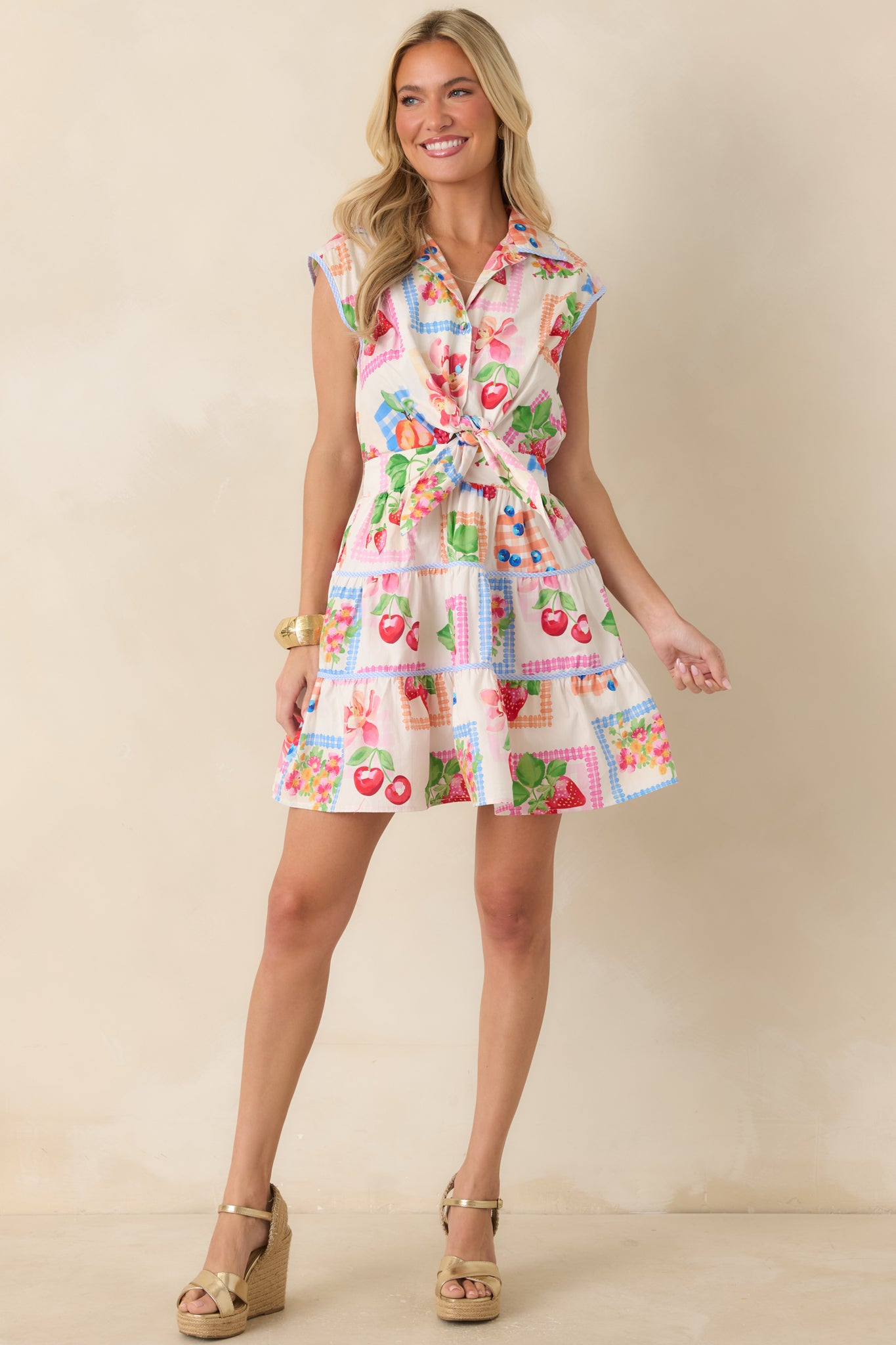 Multi fruit print mini dress featuring a collared neckline, cap sleeves, and a button-front bodice with a tiered skirt silhouette.