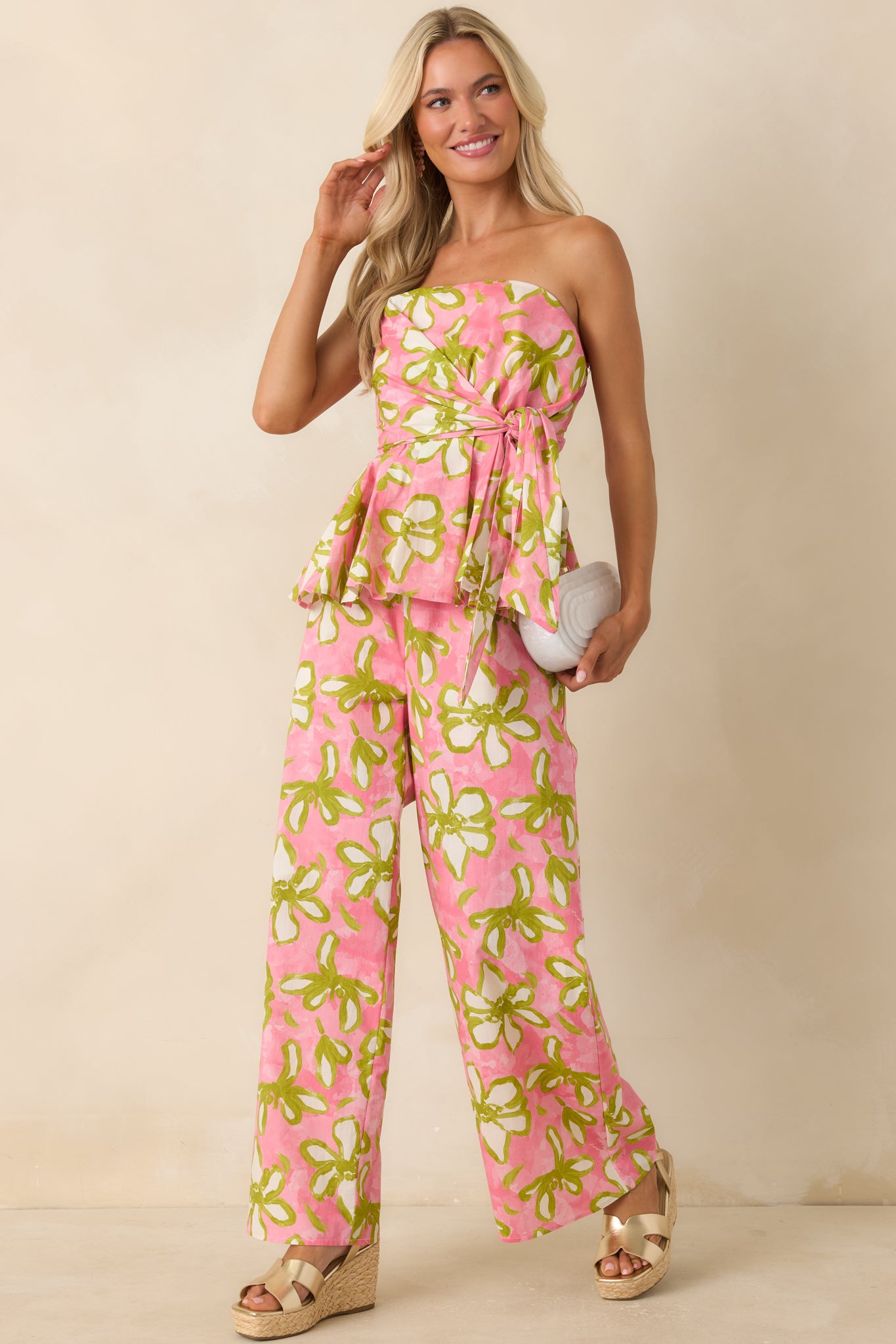 Strapless floral top featuring a vibrant pink, olive green, and ivory hand-painted print, wrap-inspired front, and feminine peplum hem.