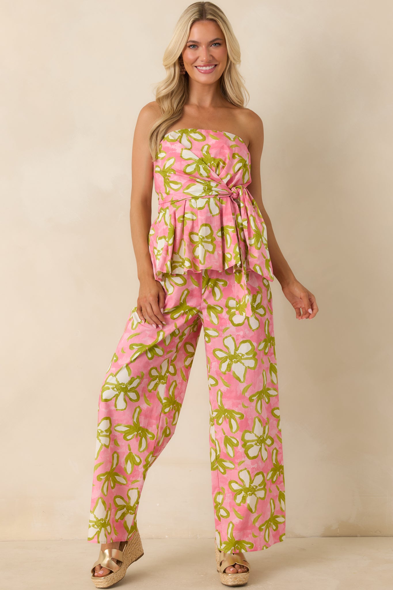 Pink and green floral strapless top showcasing a wrap-style bodice, peplum detail, and resort-ready statement print.