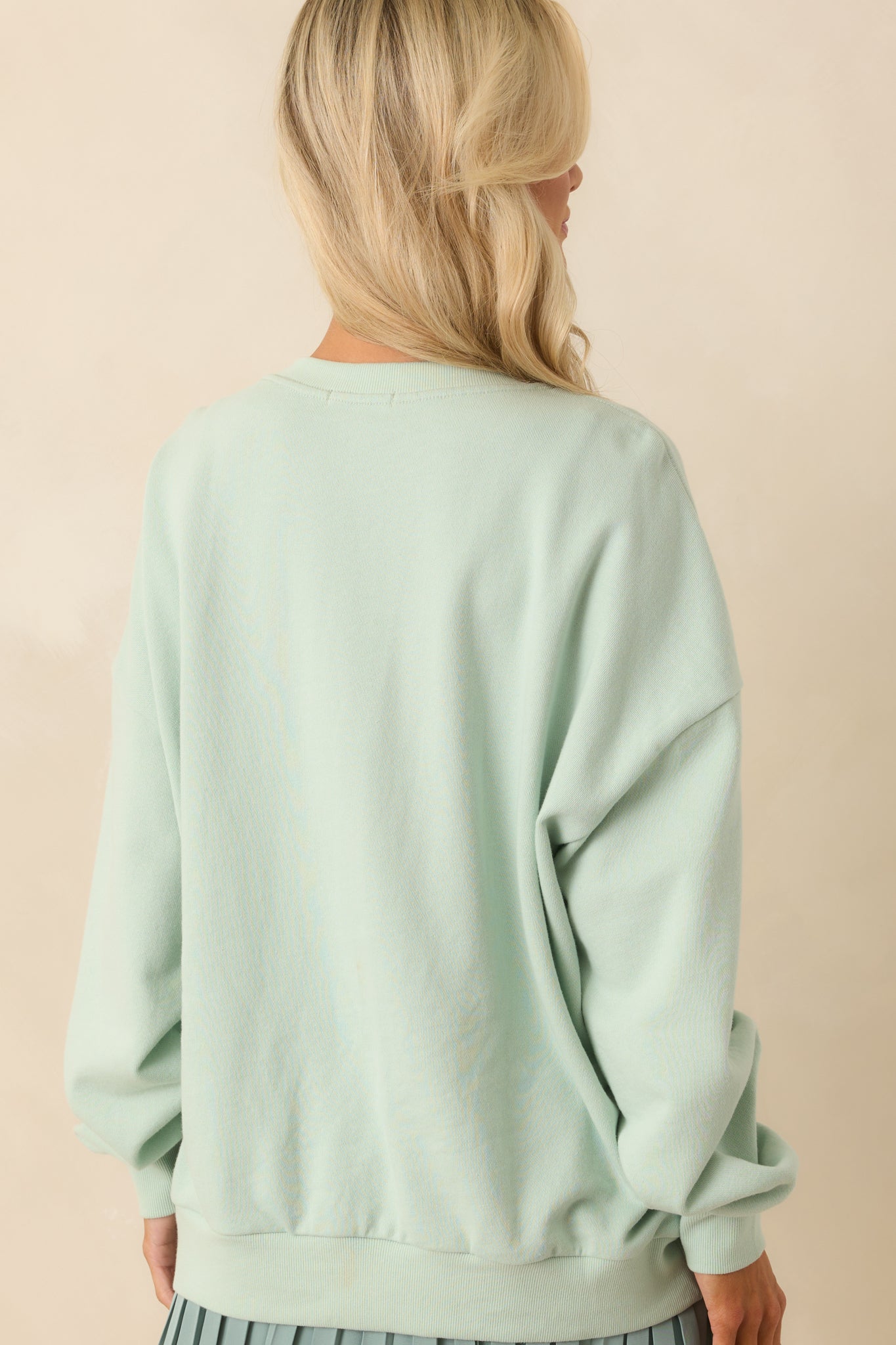 A view from behind of the sweatshirt displaying the oversized shape, smooth back, and long sleeves.