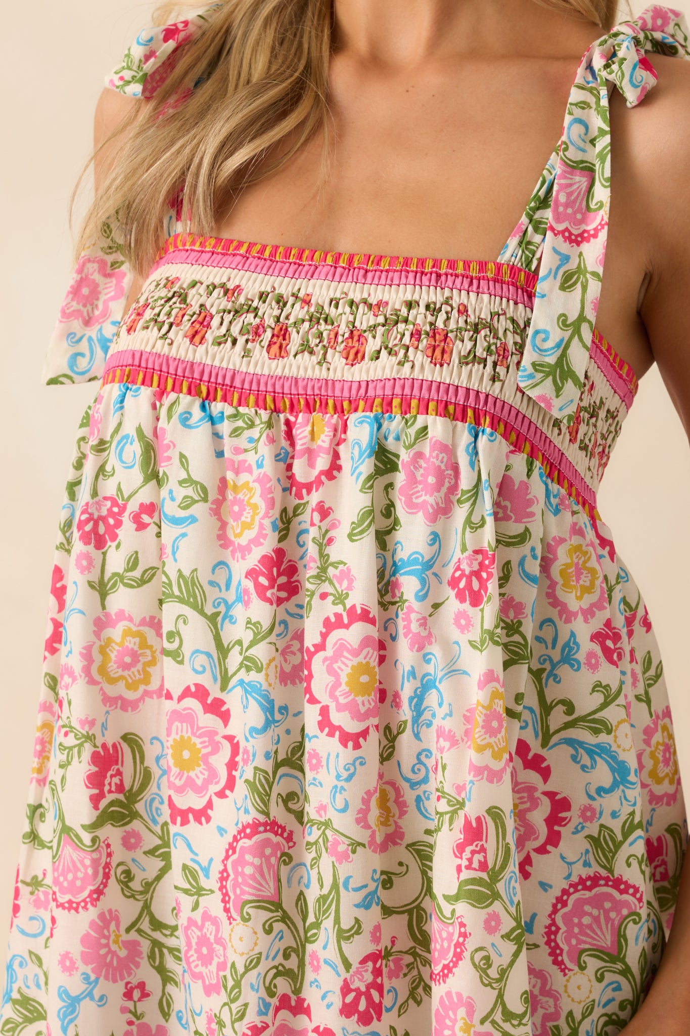 Close-up of the smocked square neckline and floral print, with a clear view of the bow strap detail.