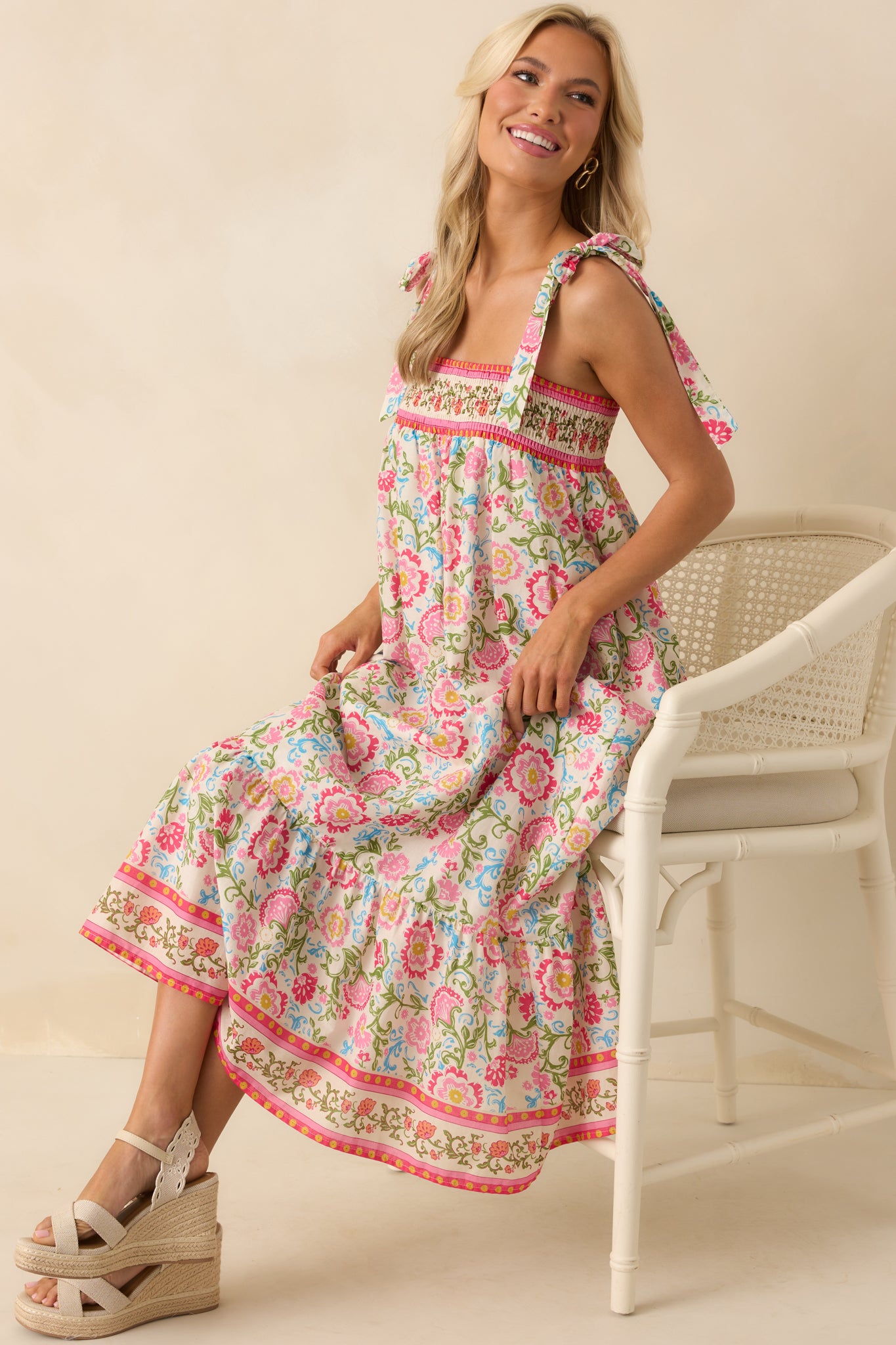 Full view of the pink maxi dress with multicolor floral print, showing the tiered skirt and self-tie bow straps.