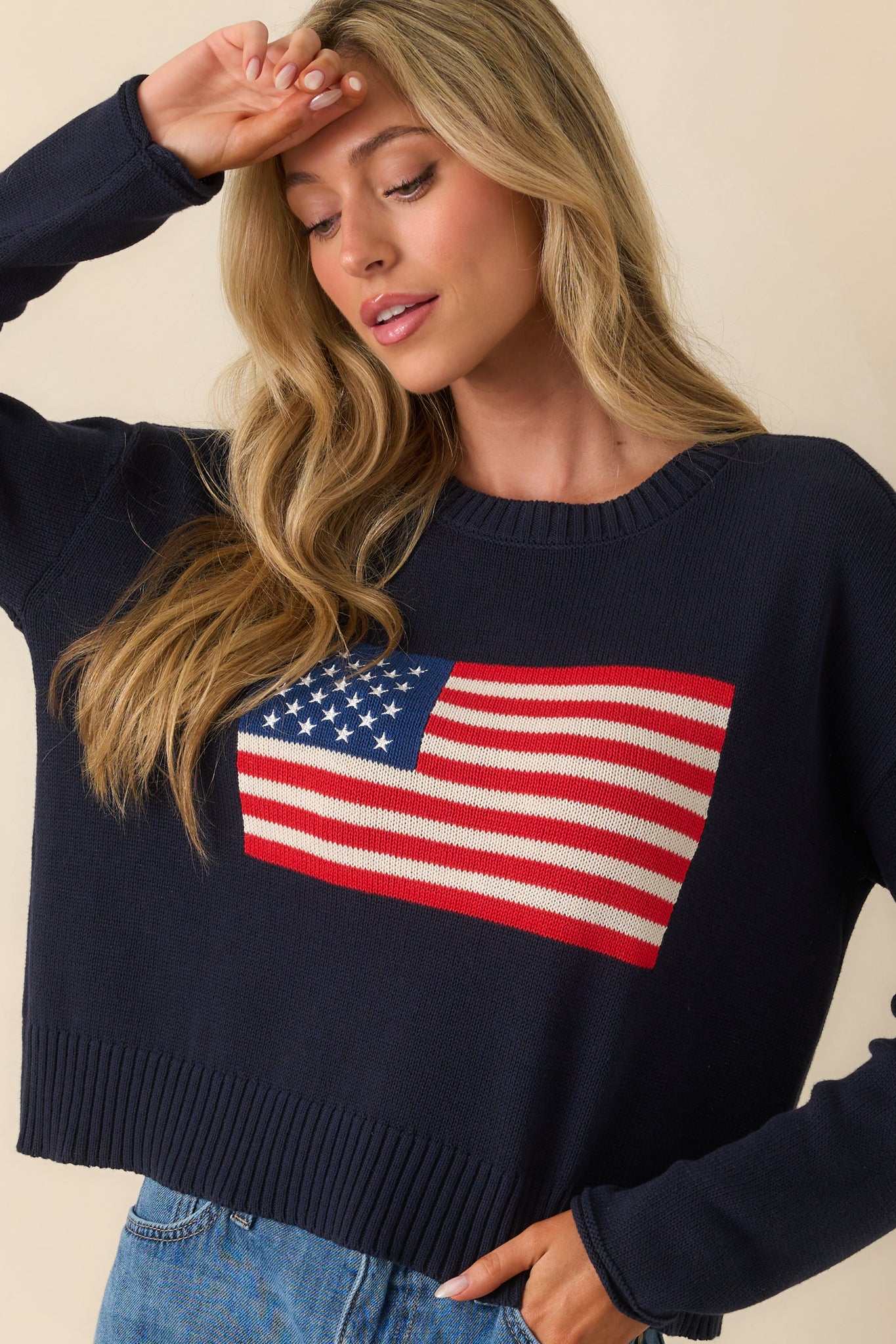 Upper cropped view of the sweater focusing on the ribbed crew neckline and the top portion of the American flag design.