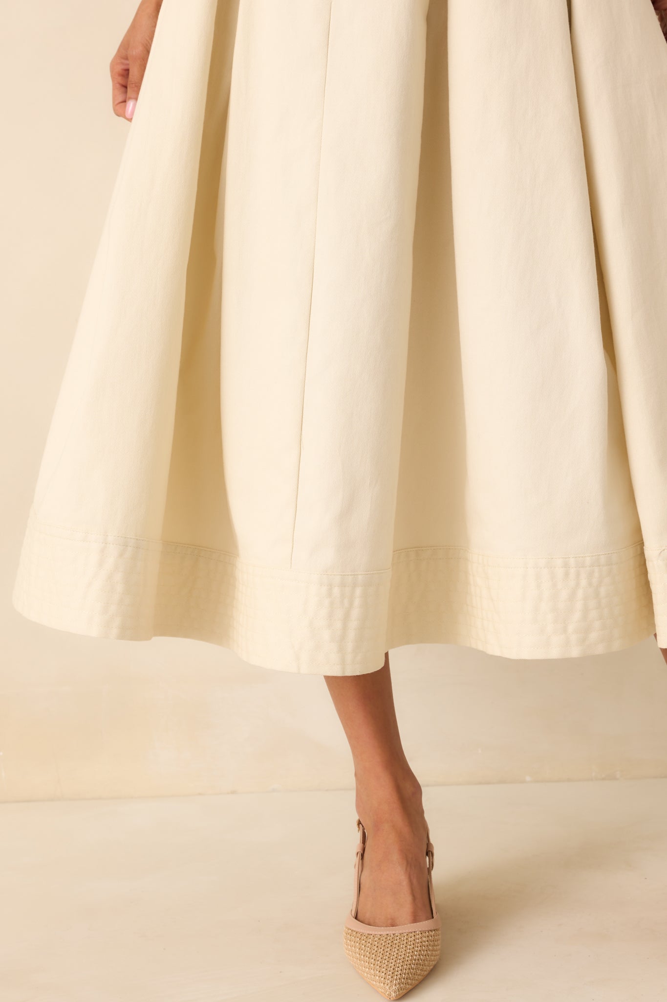 Close-up detail of the quilted bottom hem and stitching pattern on the ecru dress.