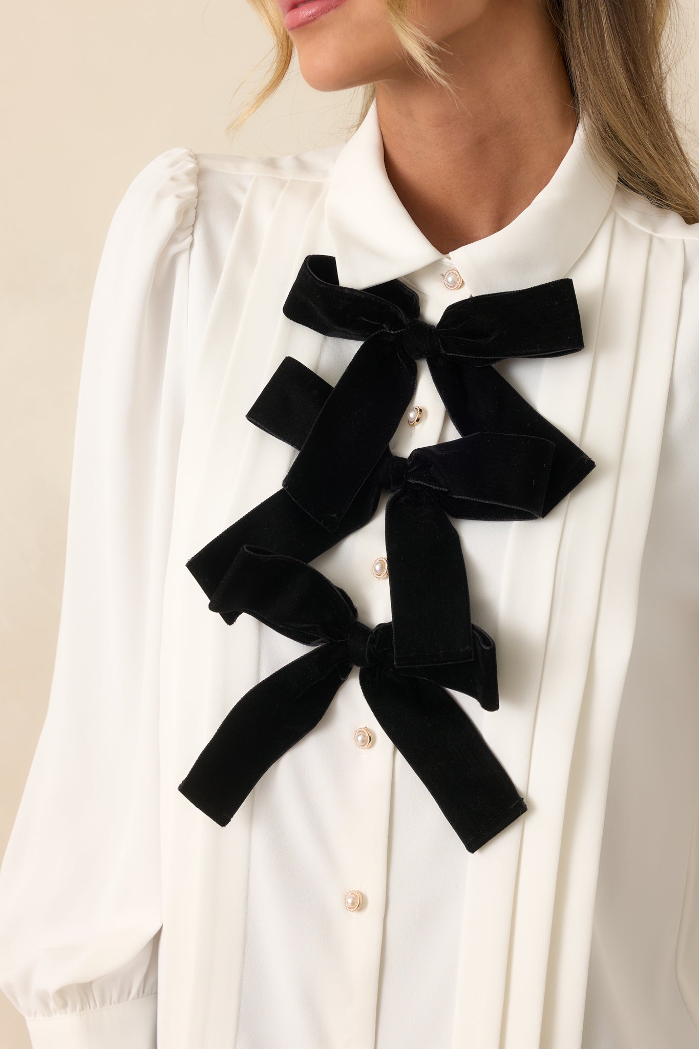 Close-up detail showing the velvet bow accents, smooth fabric, and front button closure.