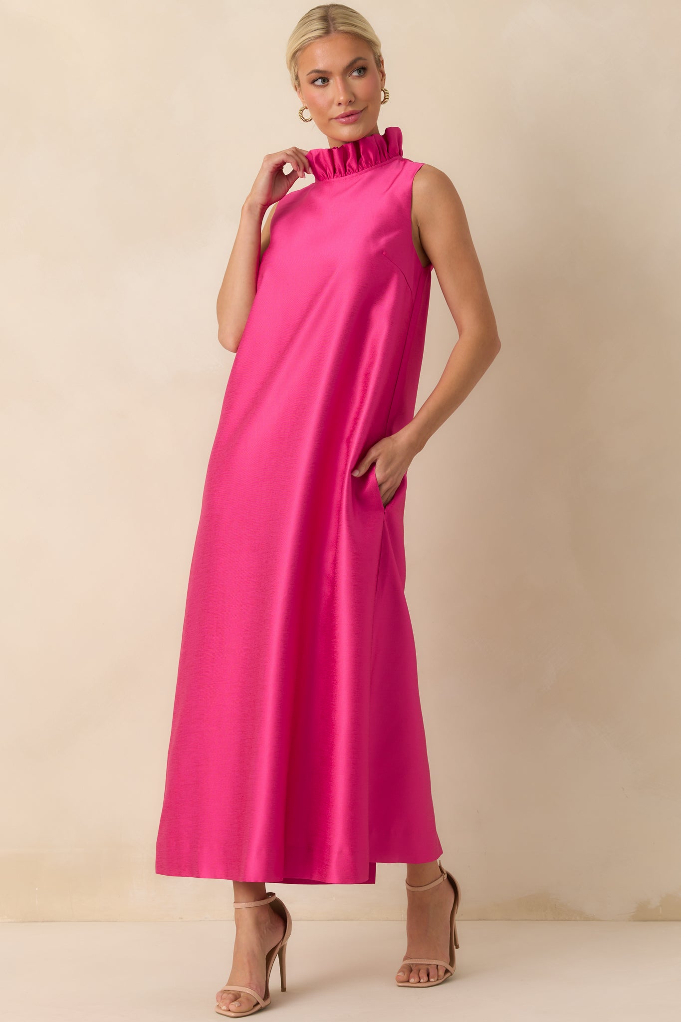 Hot pink dress with a straight-flowing maxi-length hem and ruffle detail at the neckline.