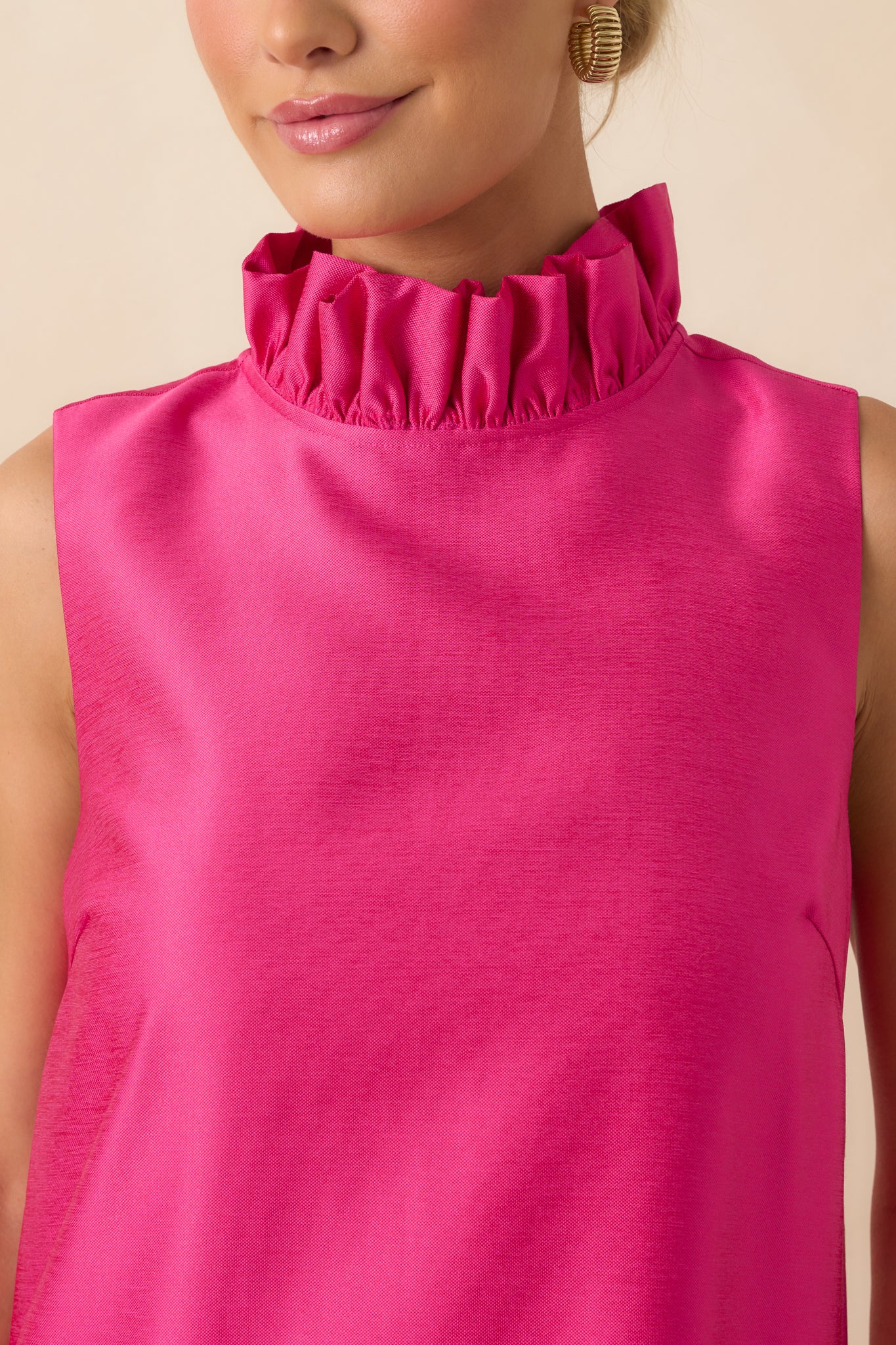 Close-up detail of the hot pink dress emphasizing the ruffled mock neckline and smooth draped fabric.