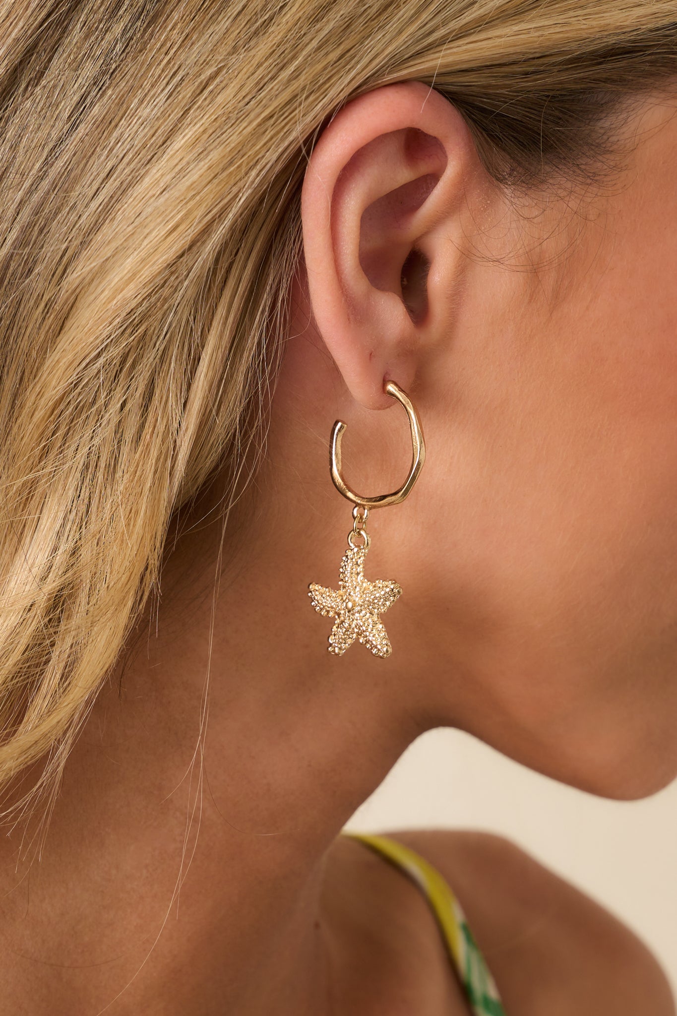 Cropped side angle showing the curved form of the open hoop and the dimensional detailing of the starfish drop.