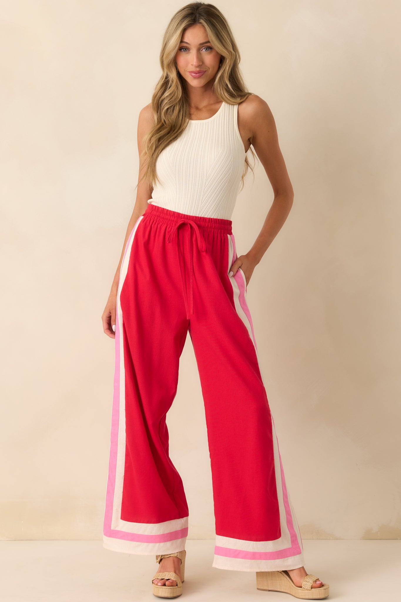 Front view of the red pants emphasizing the adjustable self-tie waistband and functional front pockets.