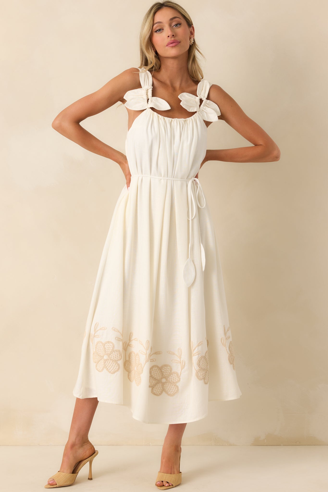 Full body image highlighting the sleeveless design, optional self-tie belt with petal tassels, and a softly cinched waist.
