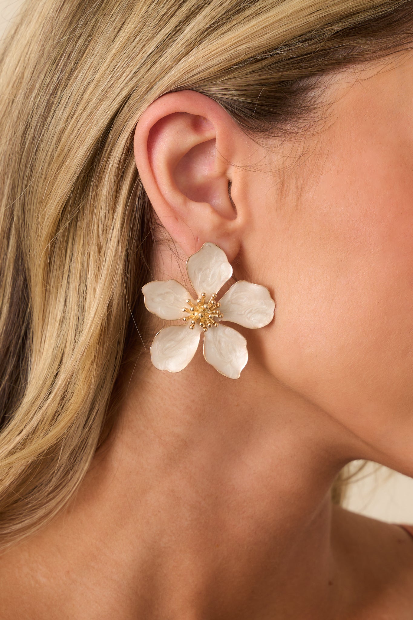 Cropped front view of the ivory flower earrings highlighting the five-pointed pearlescent petals and spiked gold center with beaded detailing.