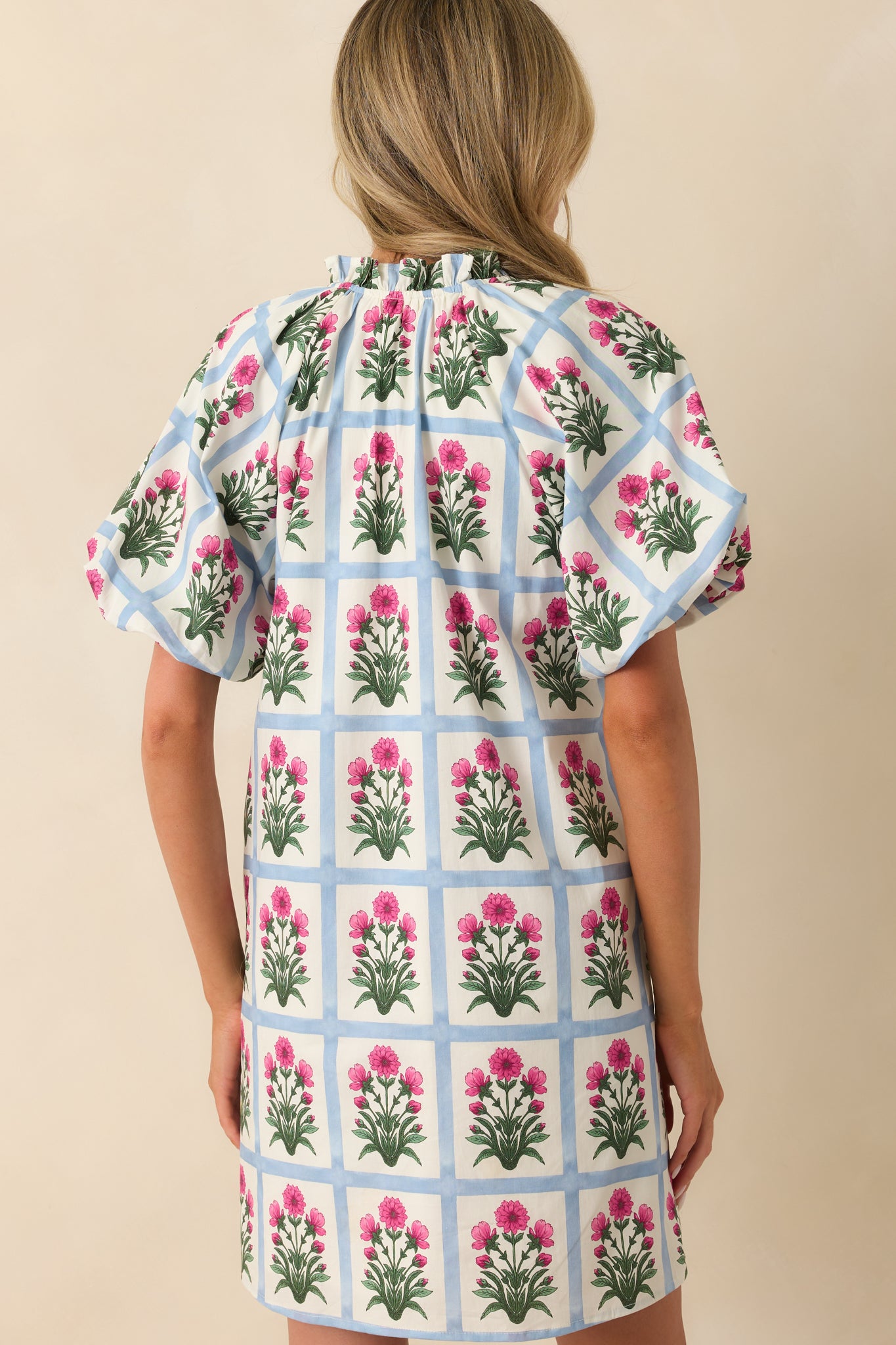 A view from behind showing the continuation of the printed pattern, short puff sleeves, and the fit of the mini dress.