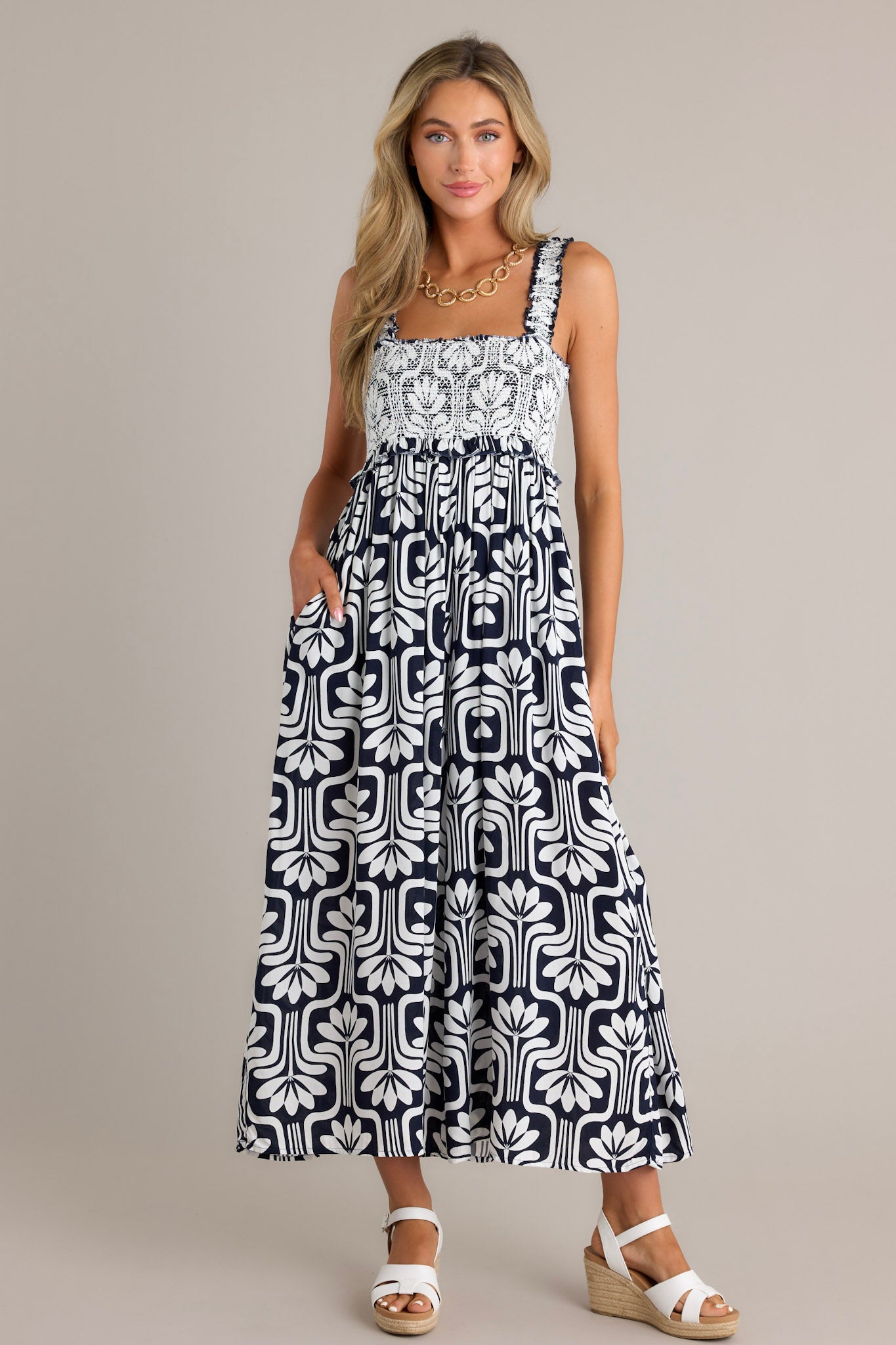 Front view of a black jumpsuit featuring a square neckline, elastic ruffle straps, a fully smocked bust, and a slightly cropped hemline.