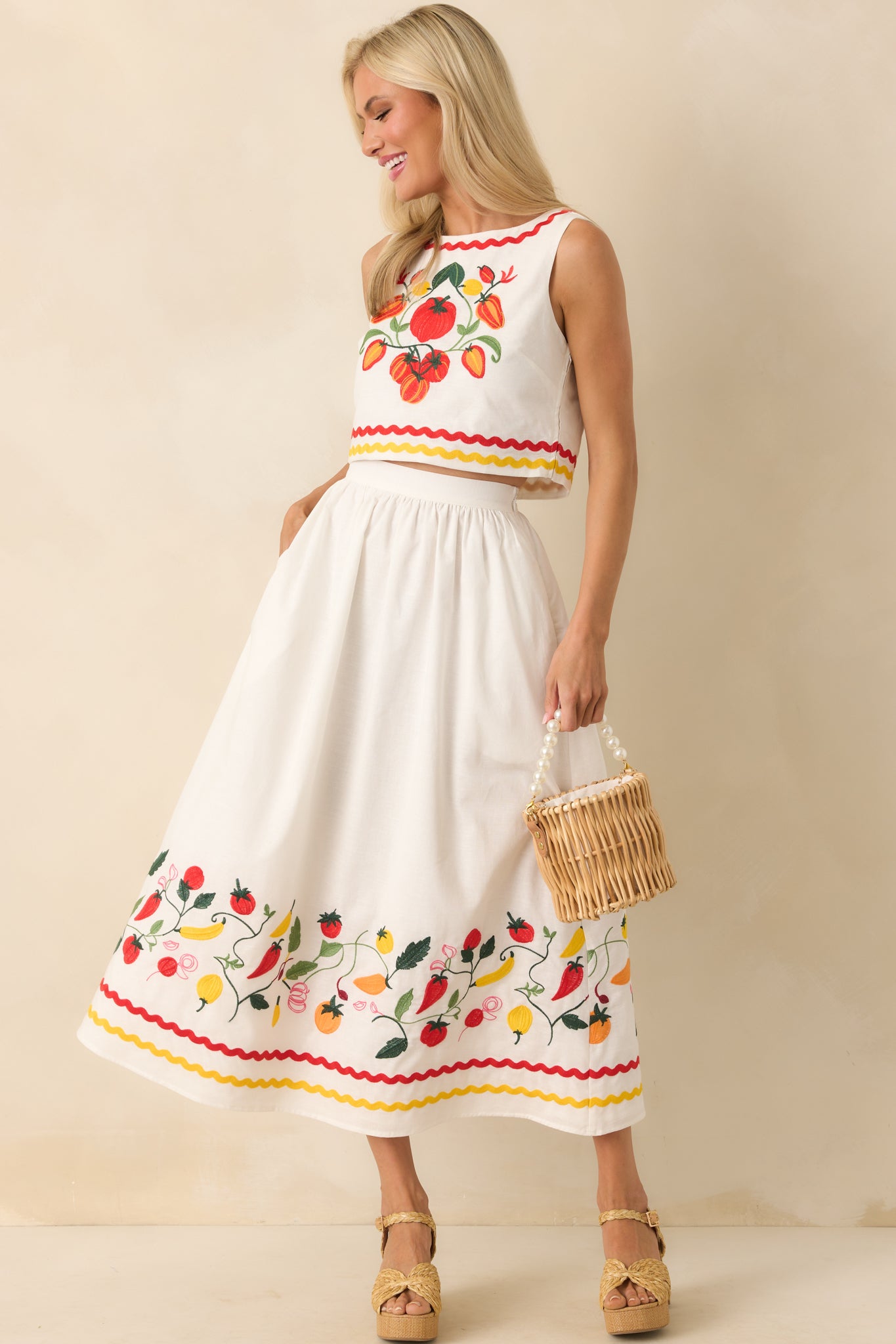 Ivory sleeveless top with multicolor vegetable vine embroidery and ric rac stripe detailing along the bottom hem, shown front-facing.