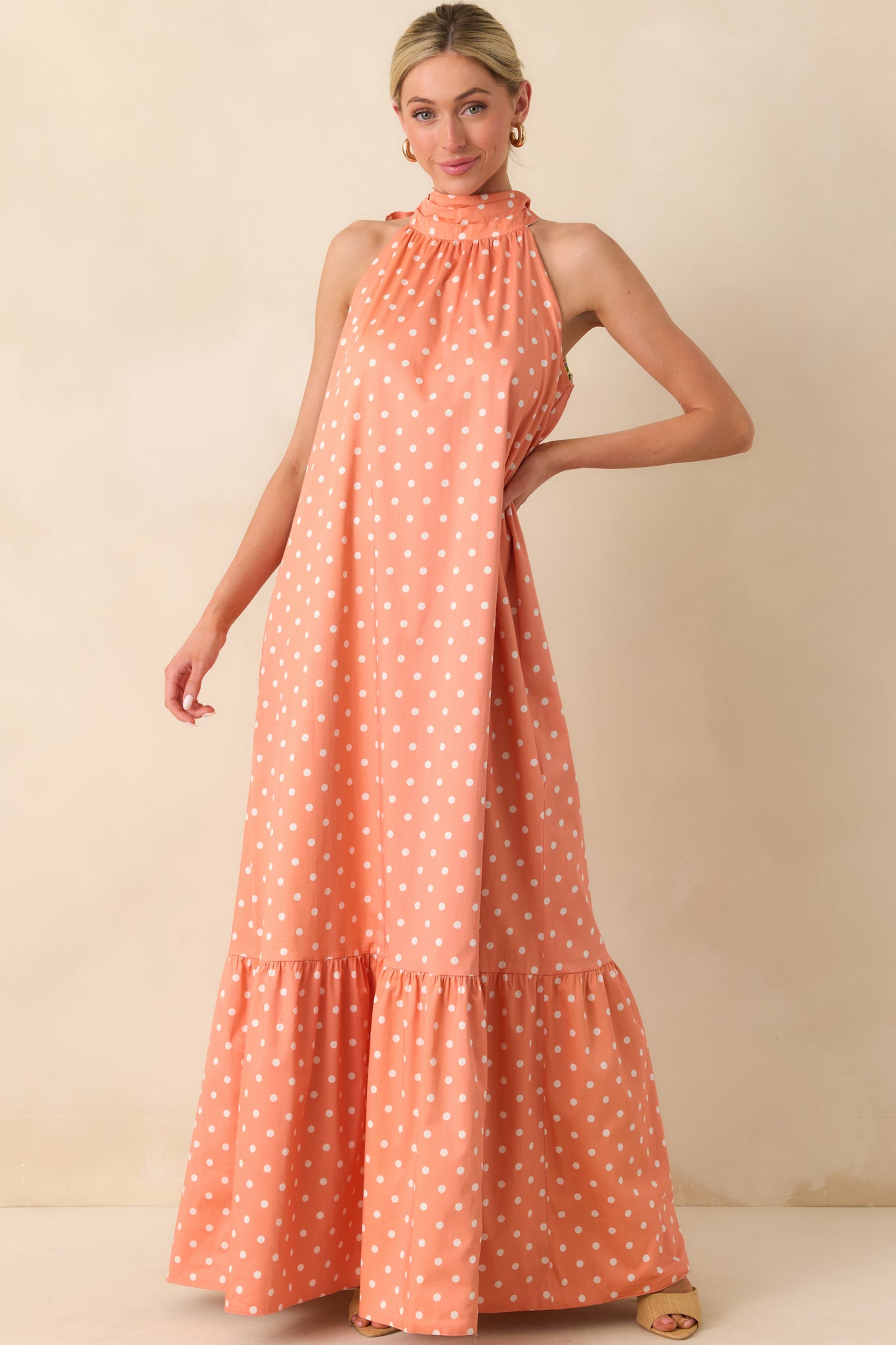 Front view of the maxi dress featuring the peach and ivory polka dot print, halter neckline, and flowing silhouette.