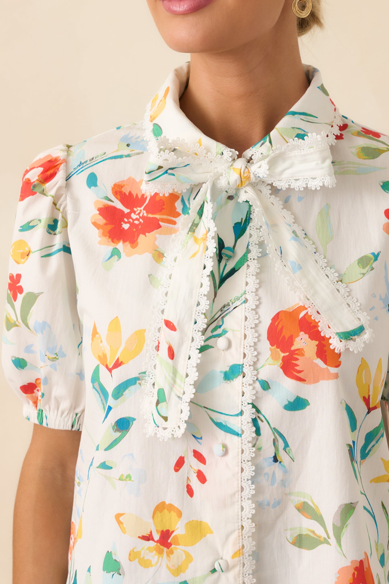 Extreme close-up of the button and lace trim stitching on the floral fabric.