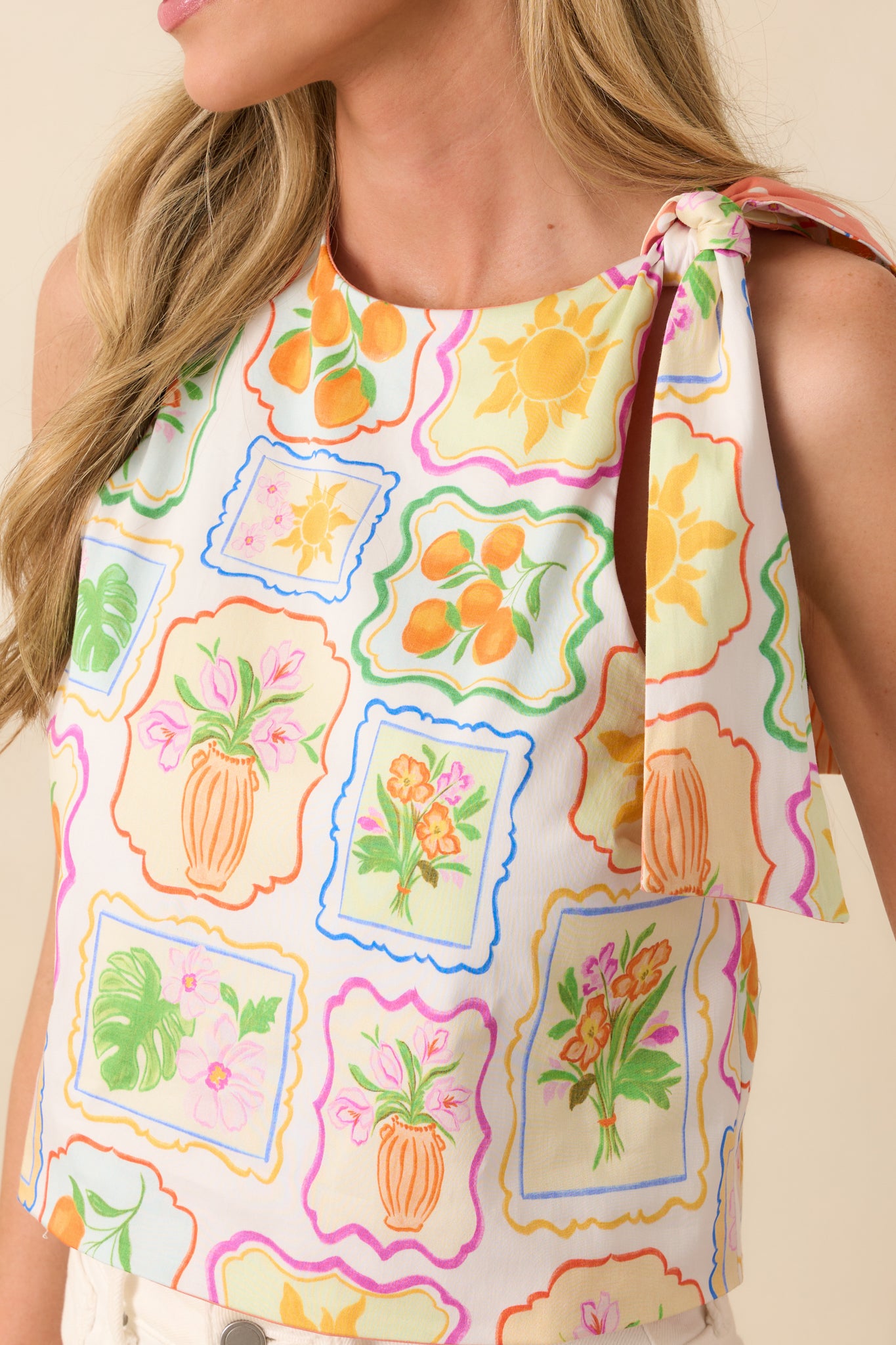 A zoomed-in shot of the round neckline and self-tie shoulder bow, showing detail of the patchwork pattern and soft fabric texture.