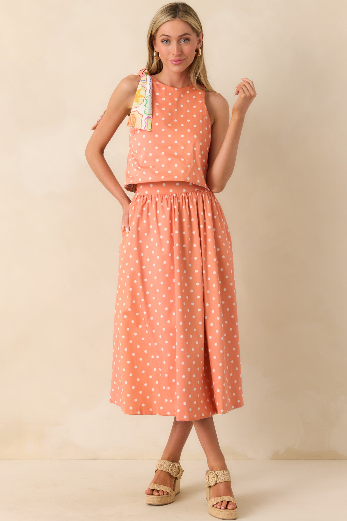 A full-length shot showing the peach and ivory polka dot side of the top, with the adjustable self-tie bow on one shoulder visible.