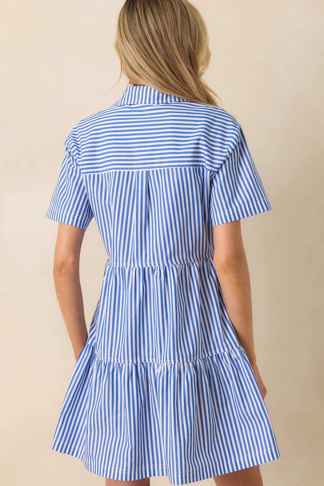 A view from behind of the blue mini dress, displaying the tiered skirt, stripe pattern, and short sleeves from the back.
