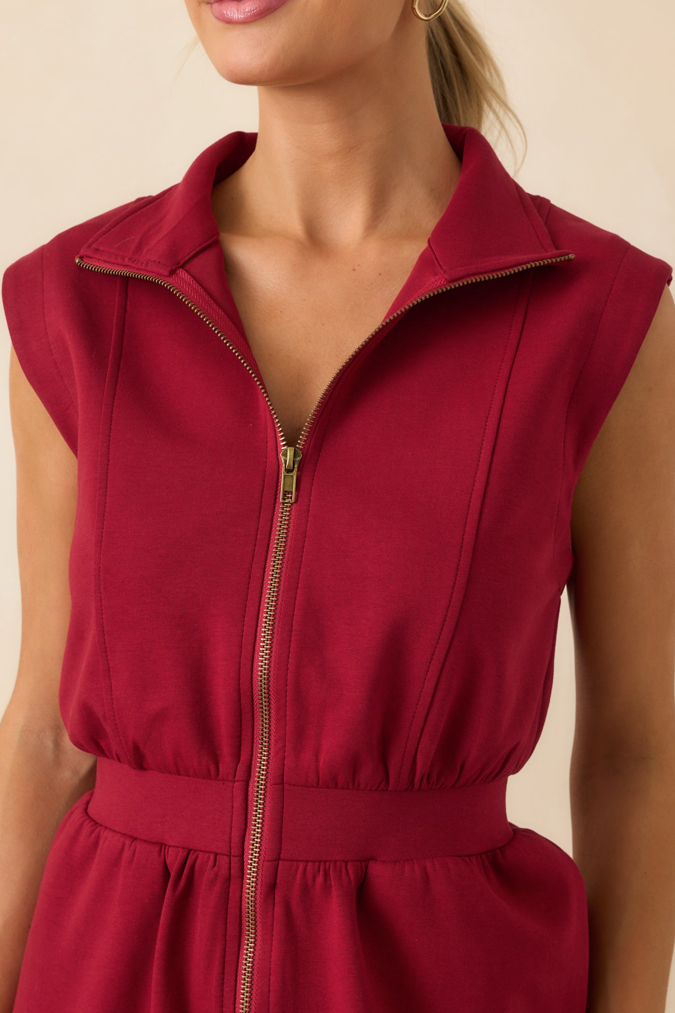 Close-up detail of the functional zipper and collar on the burgundy dress.