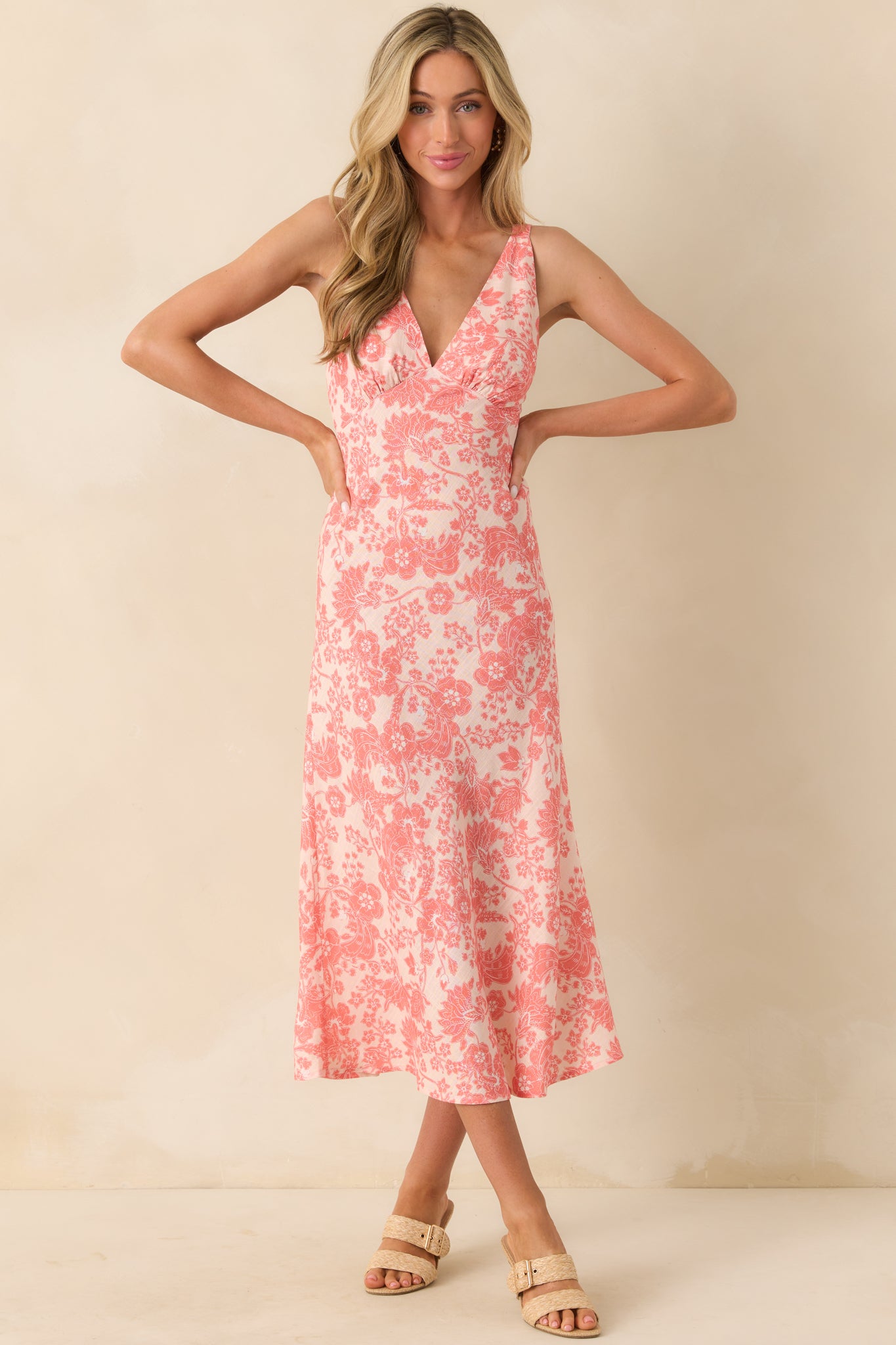 Full body front view of the pink midi dress featuring a coral floral print, deep v-neckline, and wide adjustable straps.