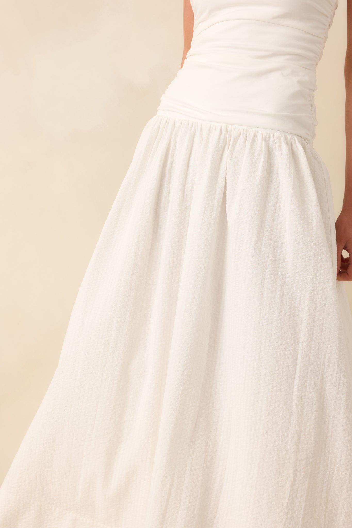 Close-up of the white seersucker skirt fabric, highlighting its textured pattern, subtle structure, and soft white lining underneath.