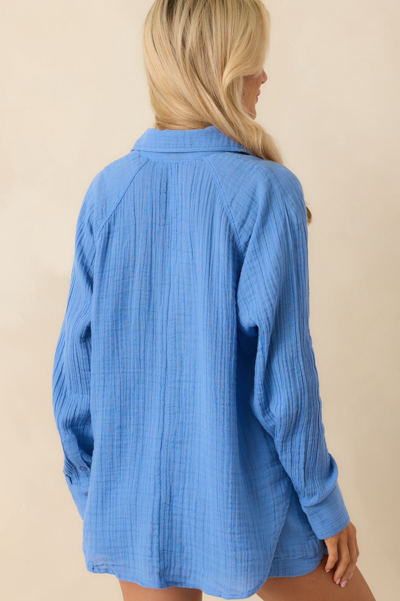 A view from behind of the blue top, displaying the long sleeves, scoop hem, and overall relaxed fit.