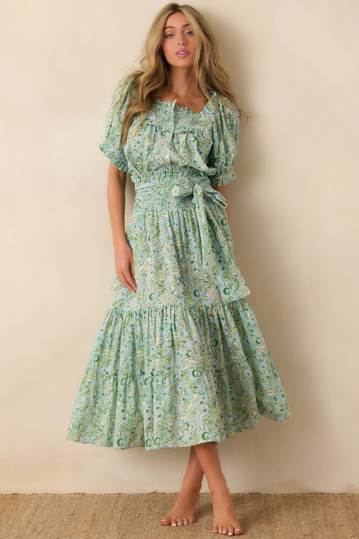 Woman wearing a green floral dress against a beige wall.