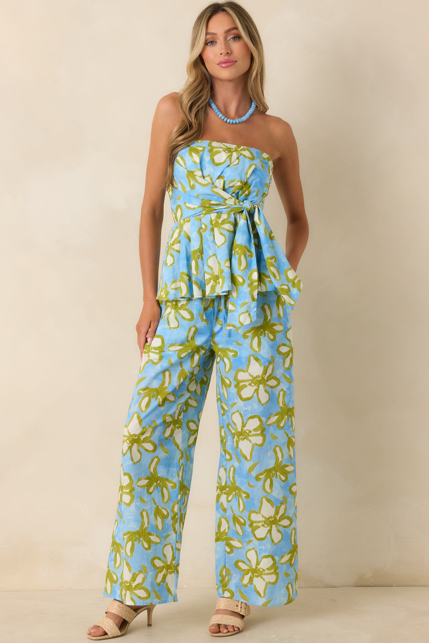 Floral cotton pants featuring a bold sky blue, olive green, and ivory print, wide leg silhouette, side pockets, and an easy pull-on design.