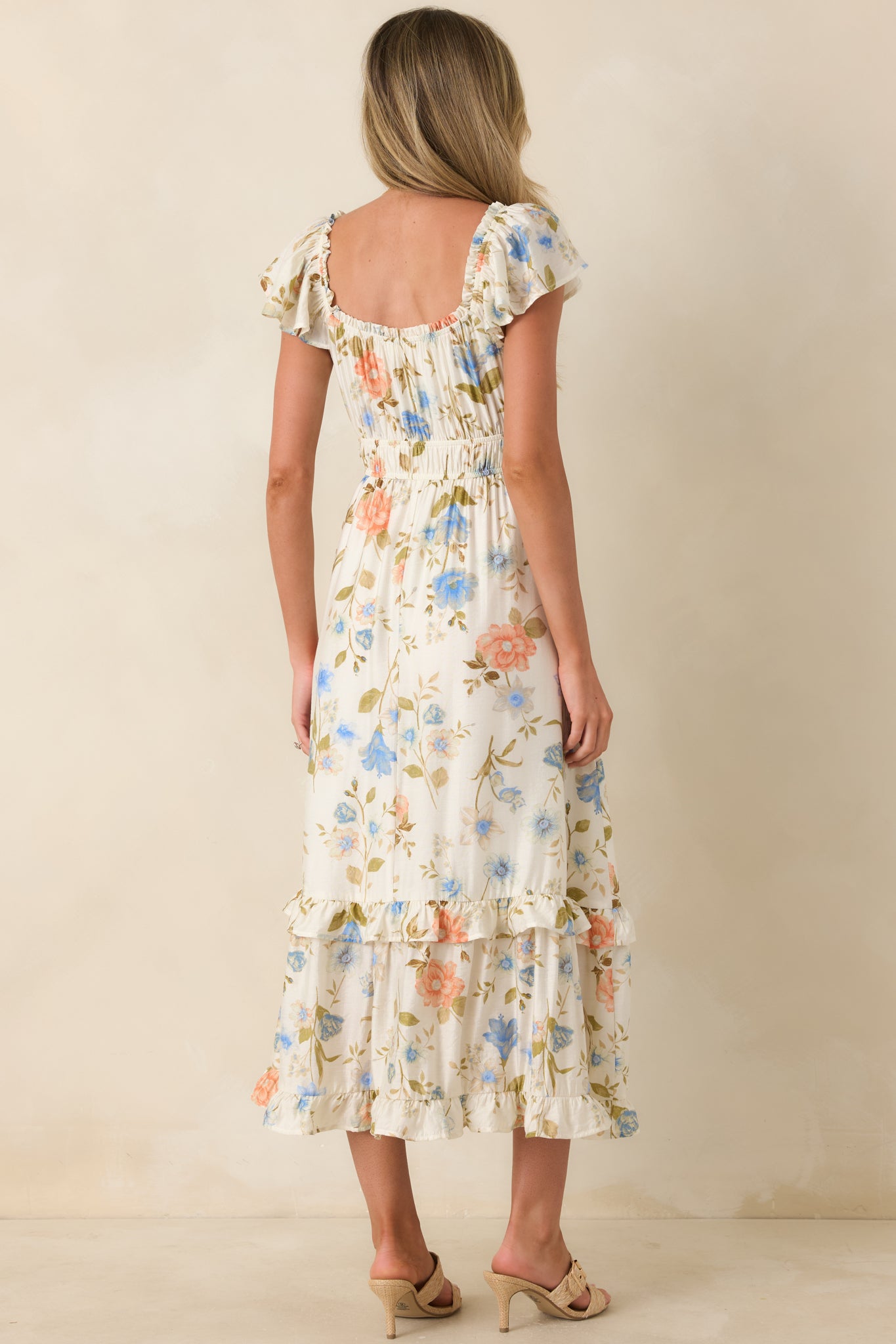 Rear view of ivory multi floral midi dress with elastic waist and tiered ruffle skirt.
