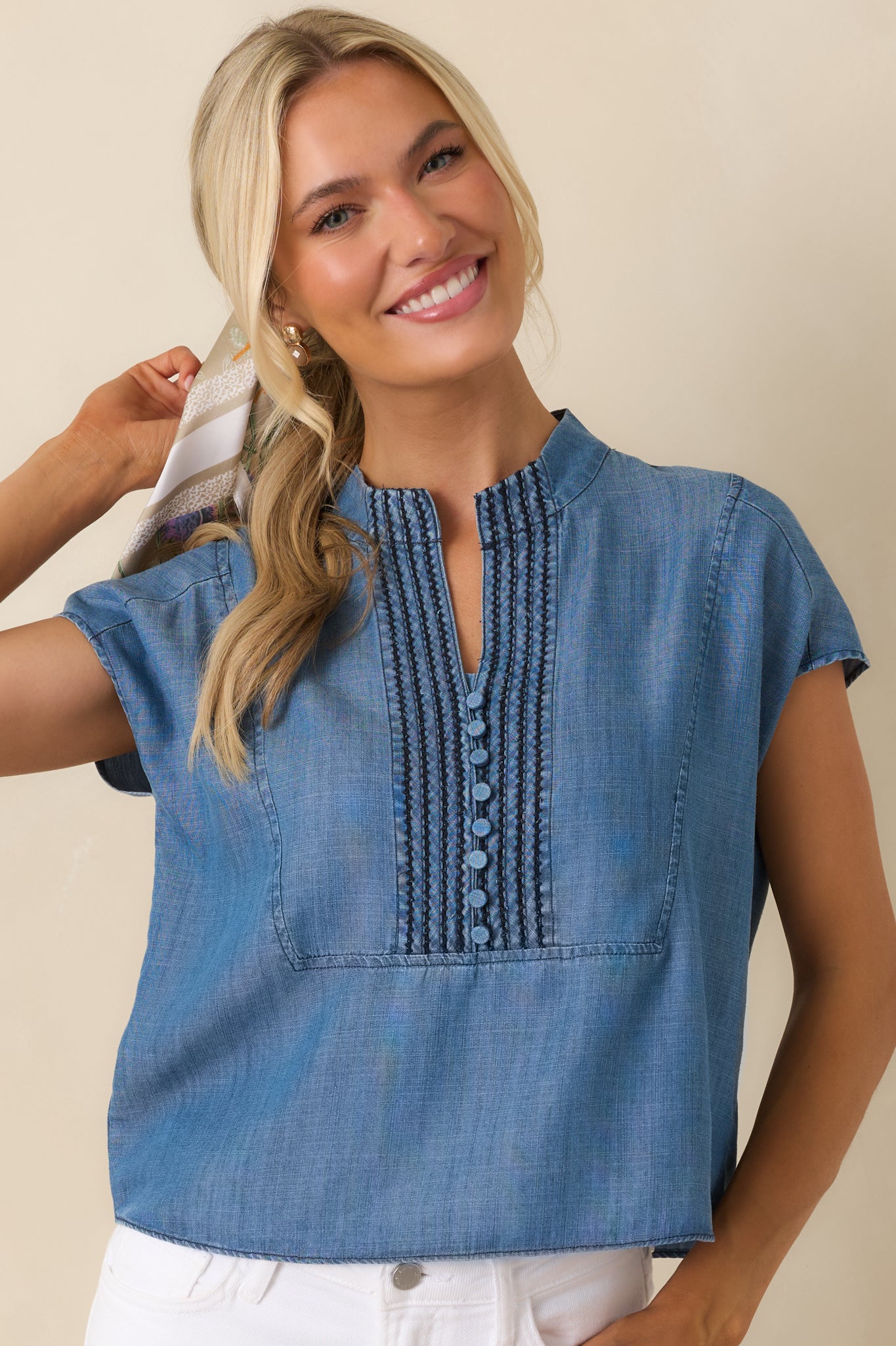 Close front view of the blue top emphasizing the short cap sleeves and relaxed silhouette.