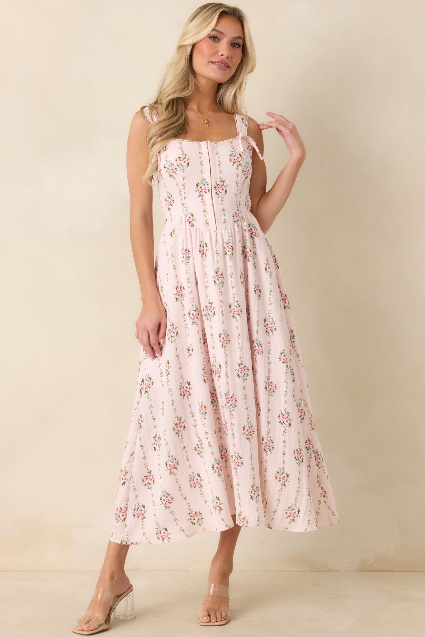 Multi floral midi dress with soft pink hues, structured bodice, and decorative tie strap accents.