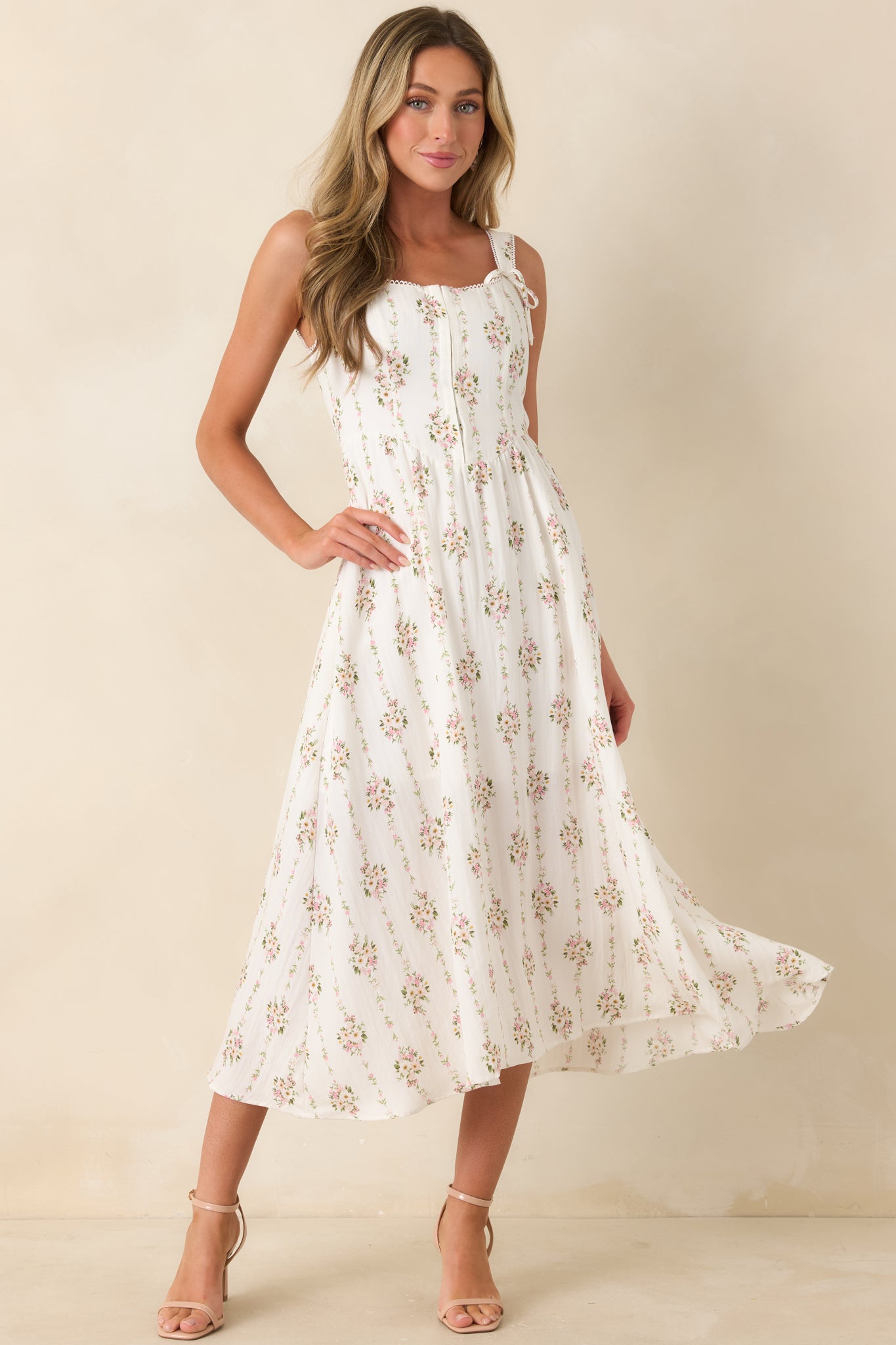 White multi floral midi dress featuring hook and eye closures down the bust, decorative tie straps, and a softly structured silhouette.