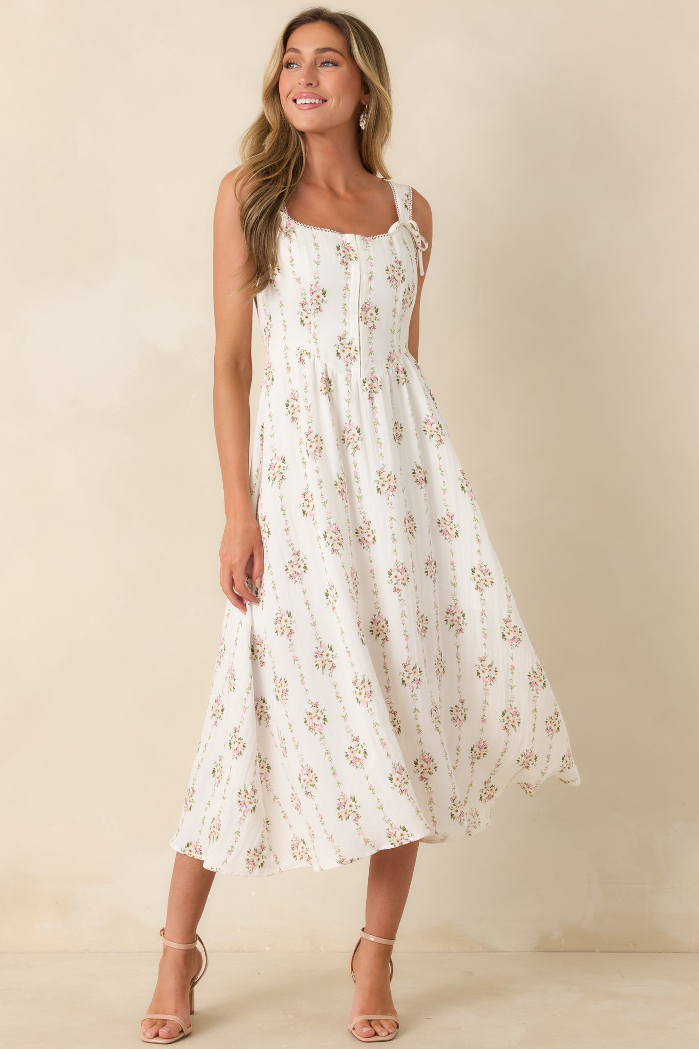 Floral midi dress with a white background, picot edge trim, fitted bodice, and delicate tie strap accents.