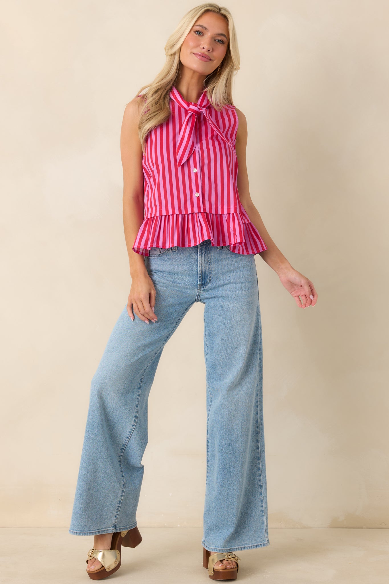 Red and pink striped cotton top featuring a sleeveless silhouette, button front closure, and ruffled hem.
