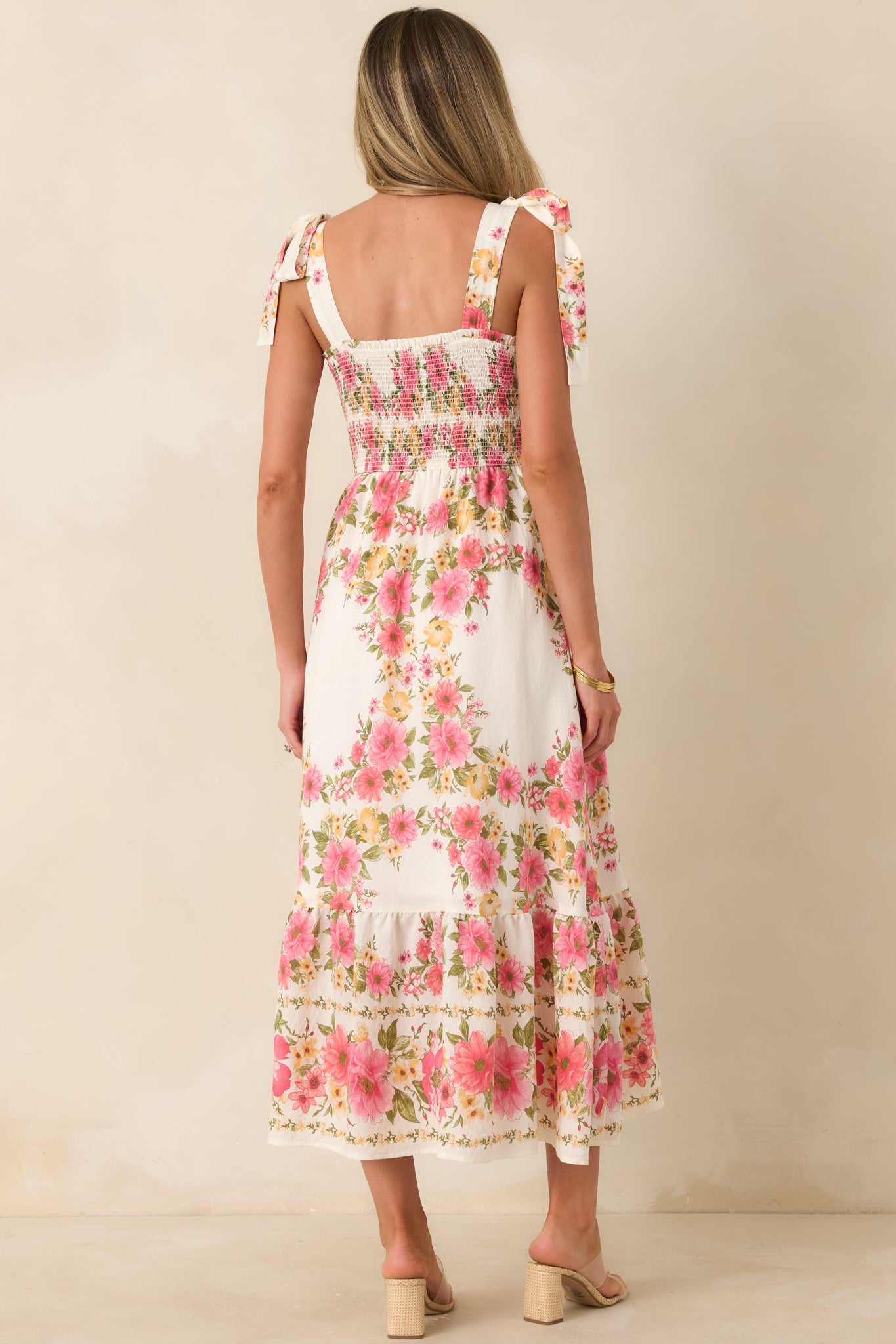 Rear view of pink and yellow floral midi dress with smocked back and flowing skirt.