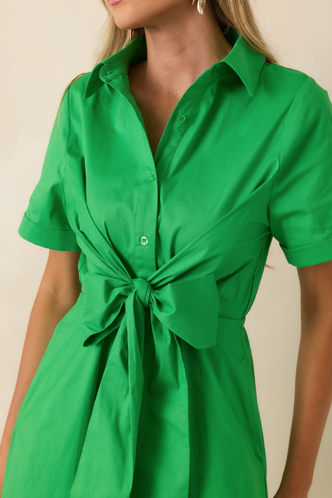 Close-up of the green cotton fabric highlighting the front bow detail, functional button closure, and smooth cotton-blend texture.