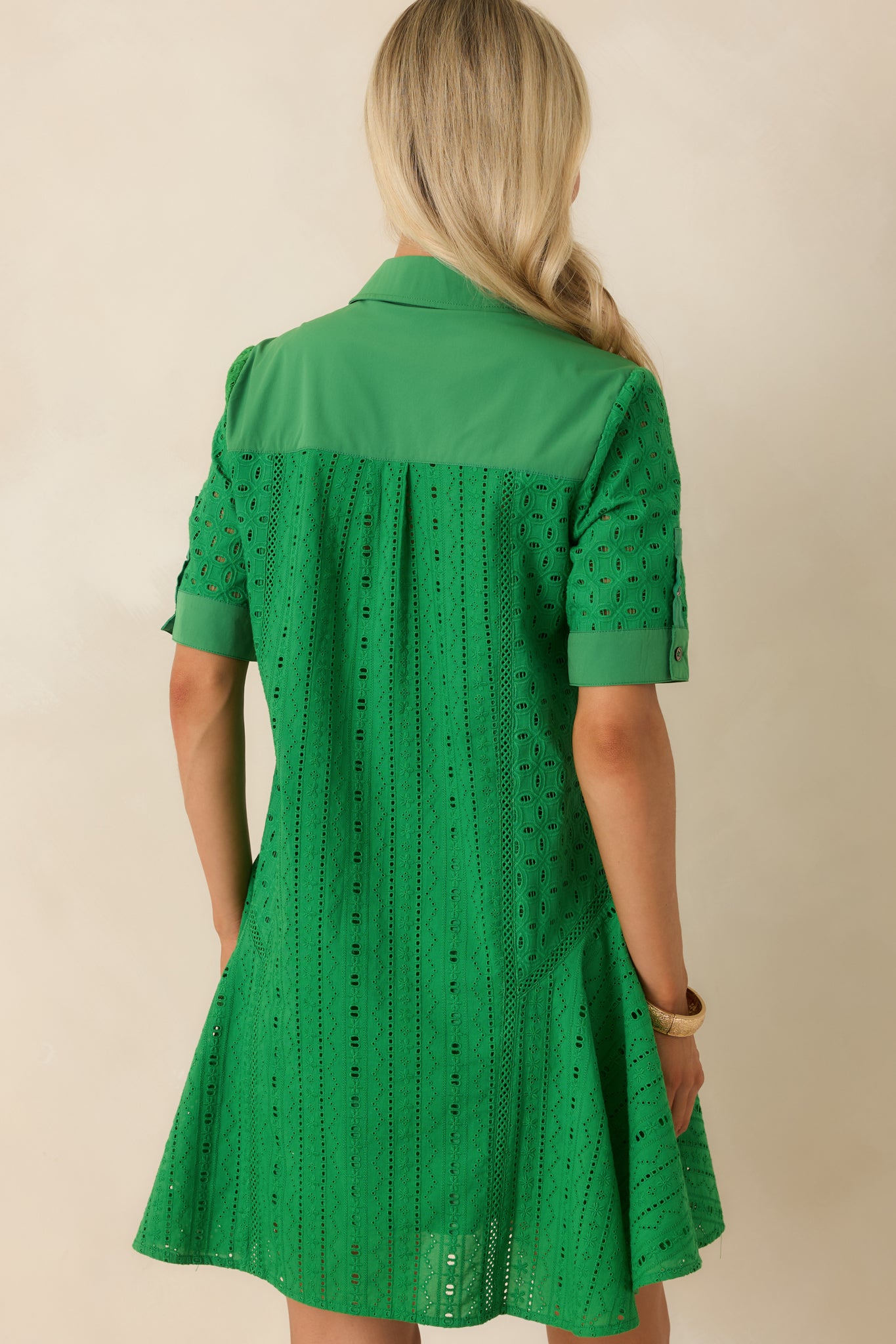 Rear view of the green eyelet mini dress featuring a fit-and-flare silhouette, short sleeves, and clean tailored finish.
