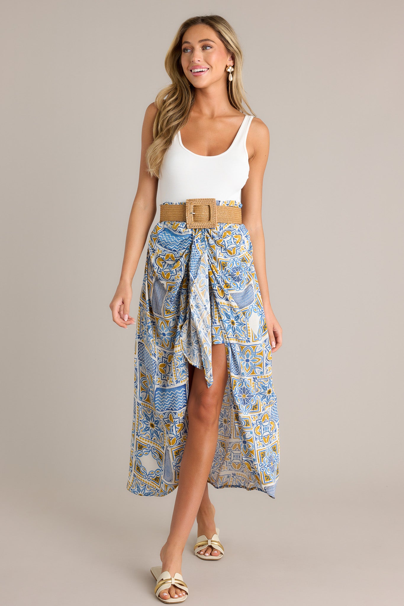 This blue maxi skirt features a high waisted design, an elastic waistband, a self-tie knot, an open front, a short skirt underneath, and a unique print.