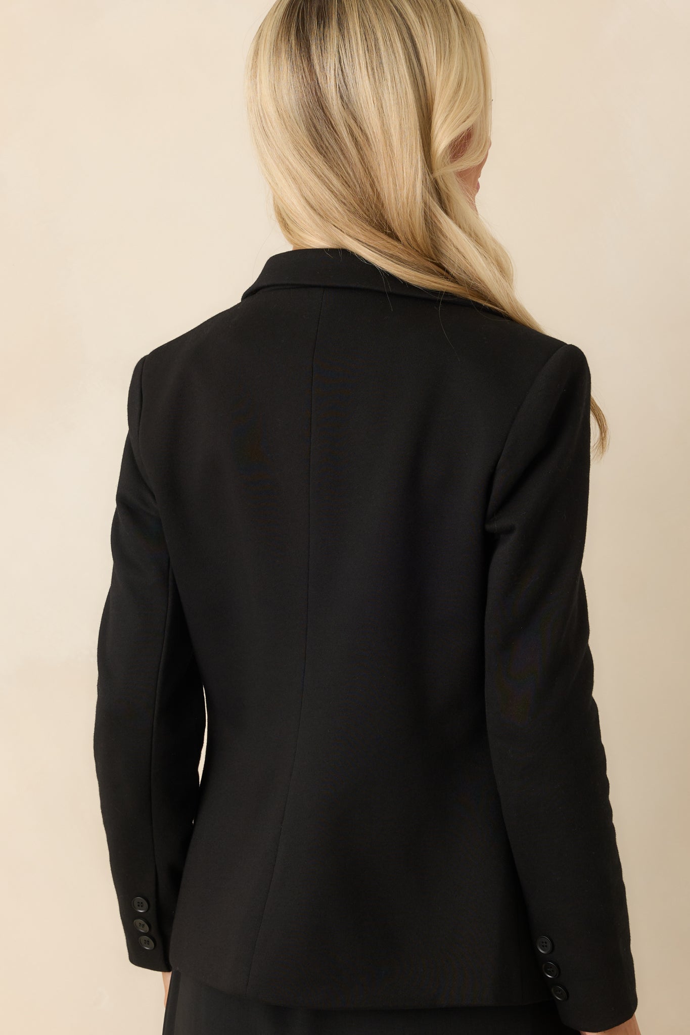 Back view of the black blazer showcasing the clean lines and the overall structure, emphasizing the padded shoulders.