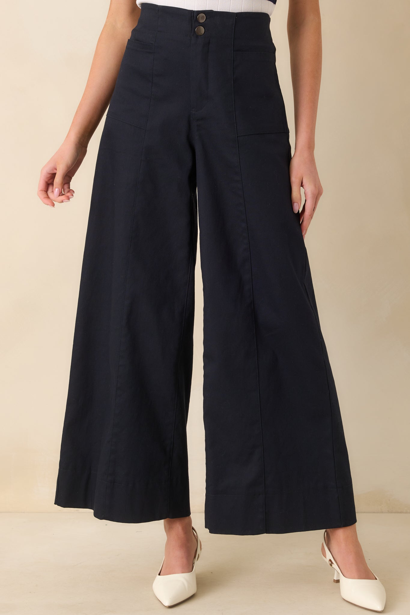 Cropped front view focusing on the high waist and button zipper closure of the navy pants.